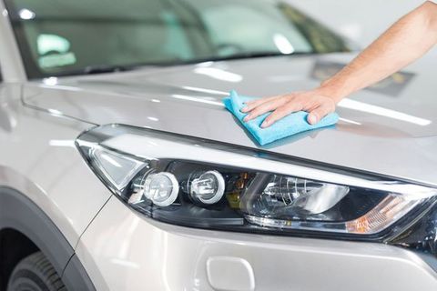 a person is cleaning the hood of a car with a cloth