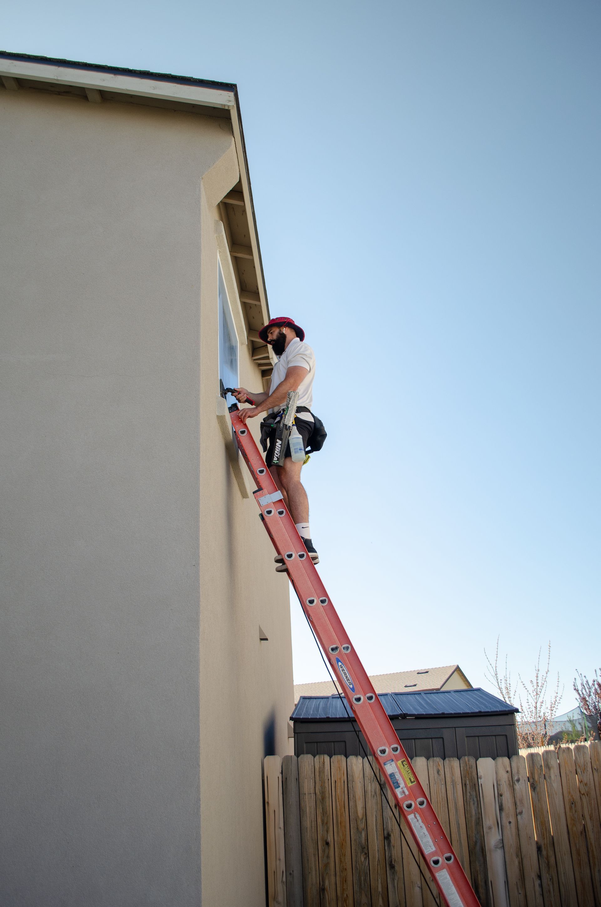 A man is standing on a ladder on the side of a building.