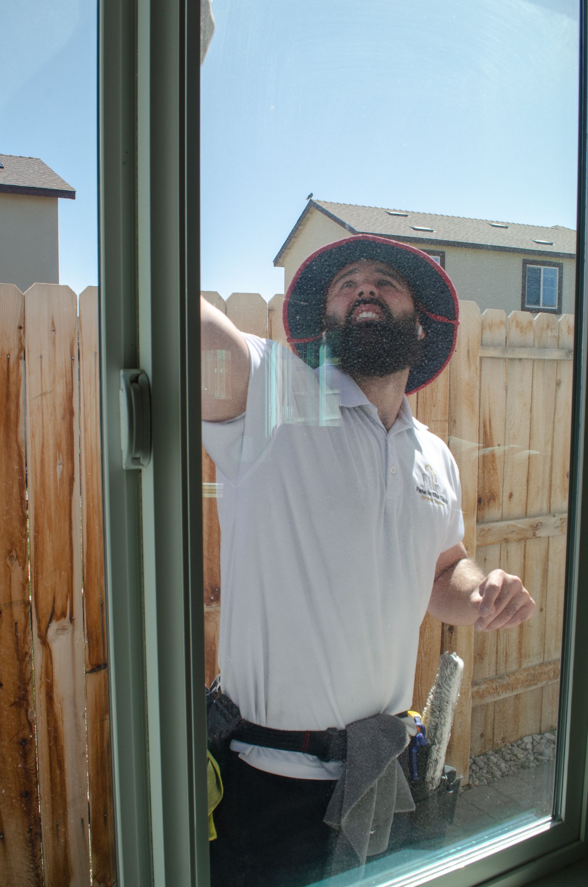 A man with a beard is cleaning a window with a towel.