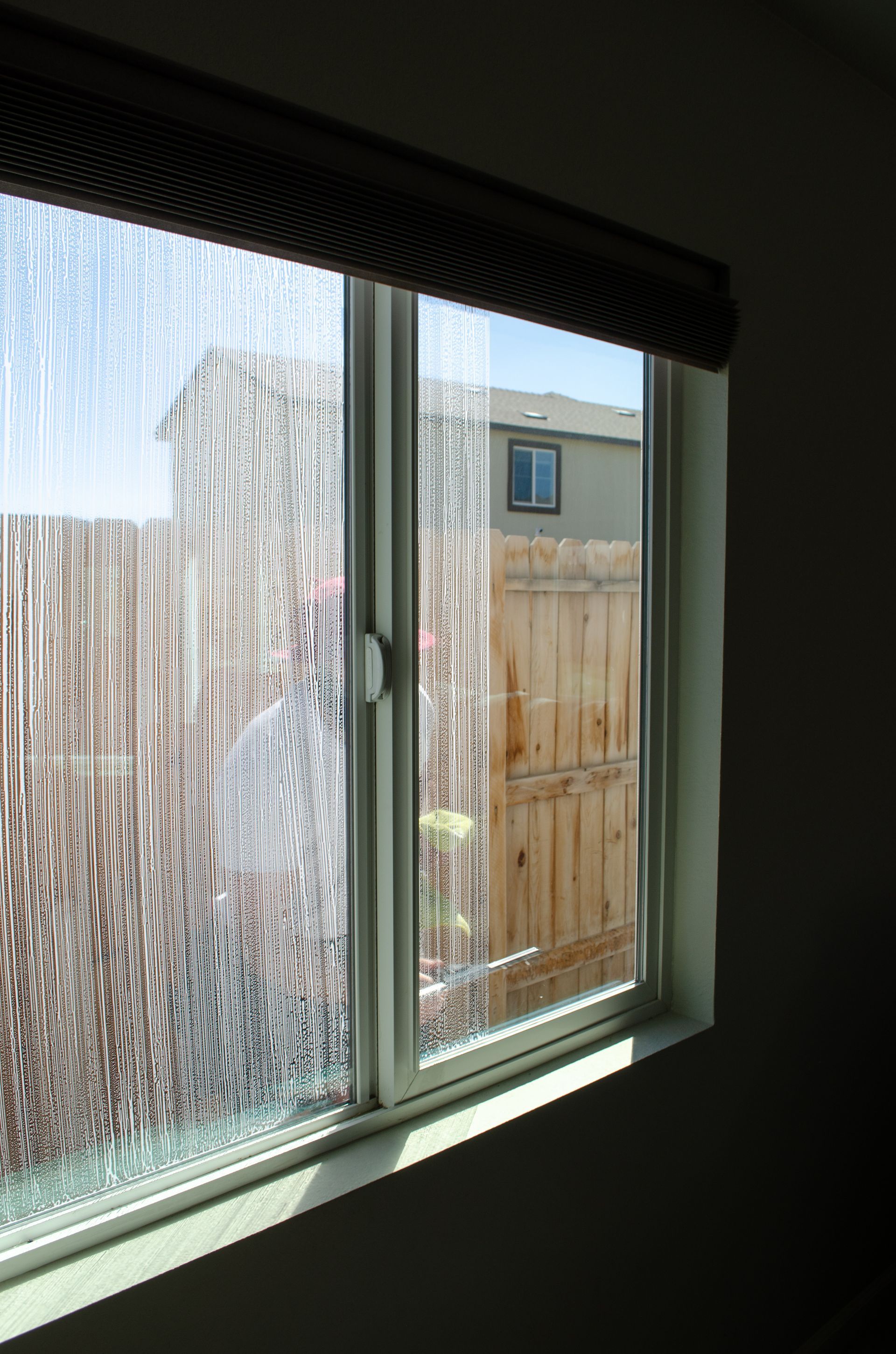 A window in a room with a fence in the background.