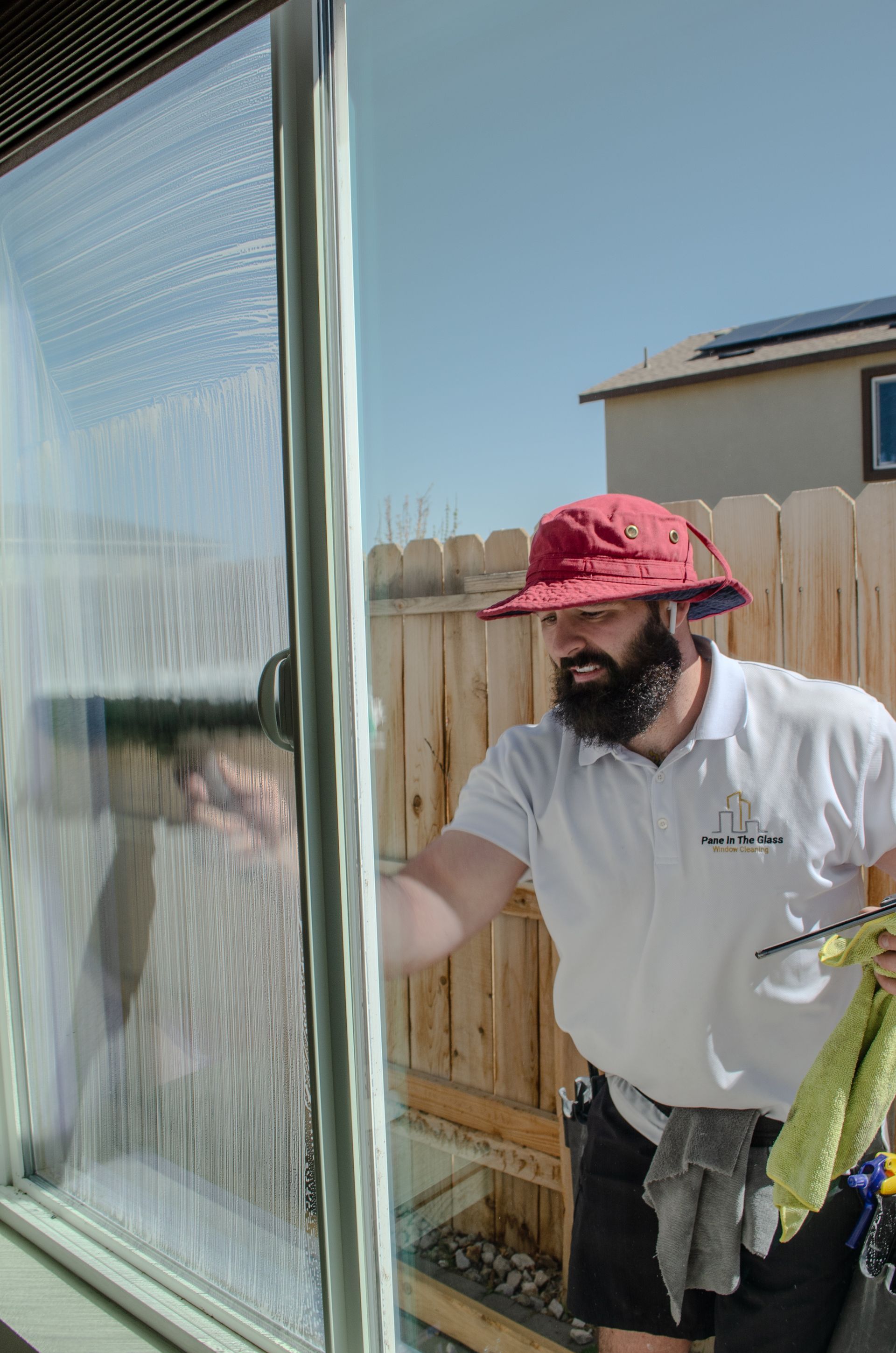 A man with a beard is cleaning a window with a squeegee.