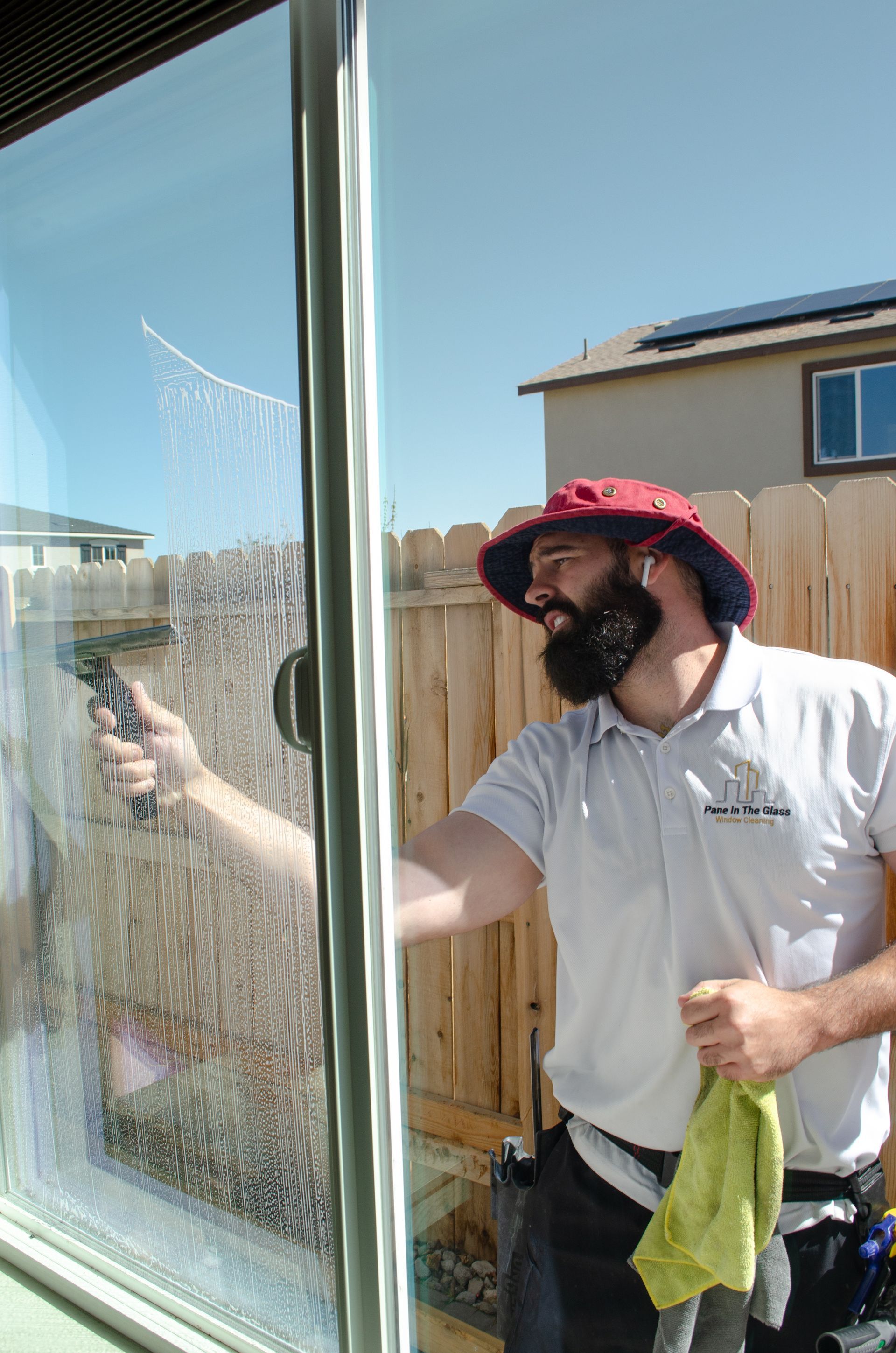 A man with a beard is cleaning a window with a spray bottle.