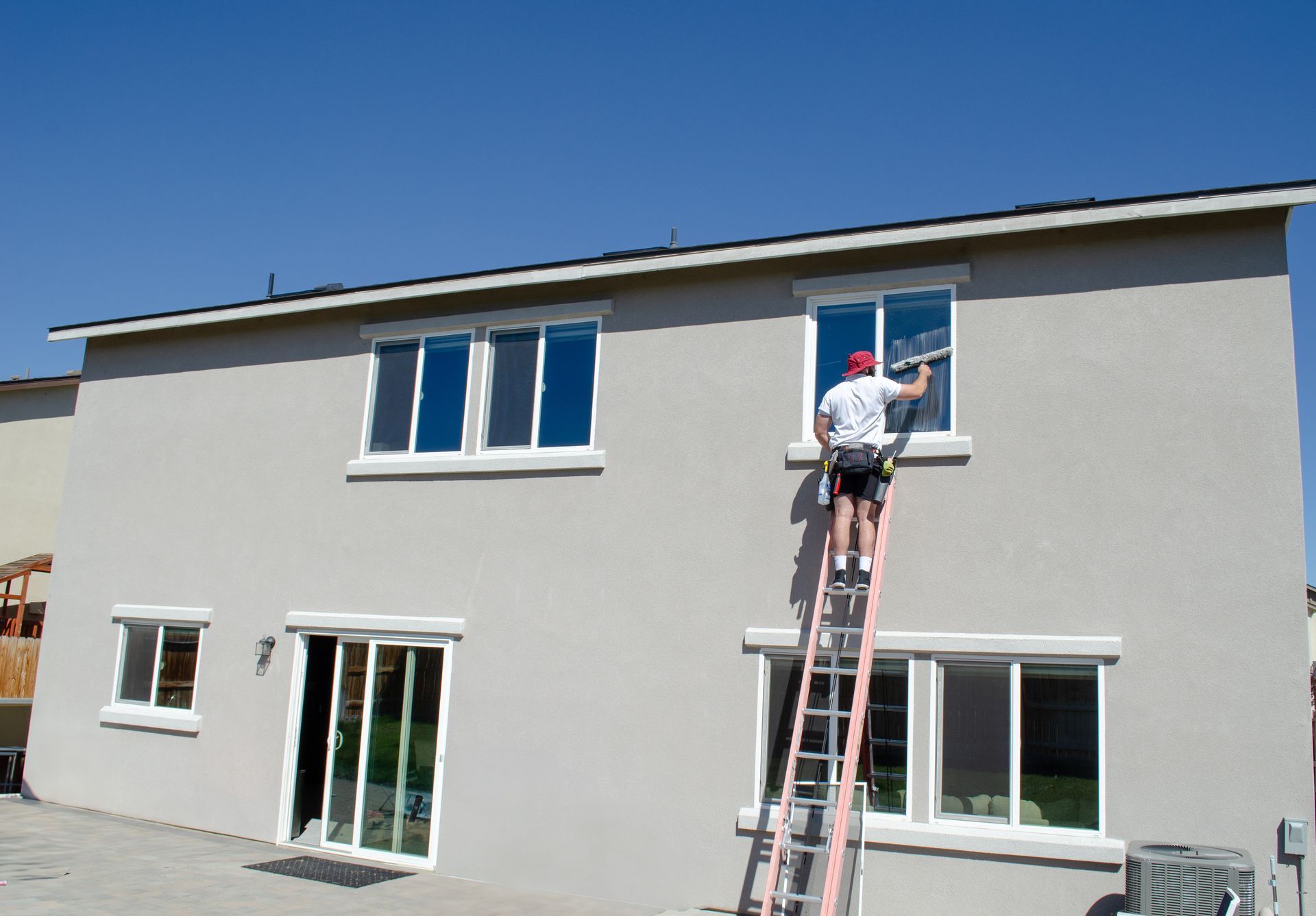 A man on a ladder is cleaning the windows of a house.