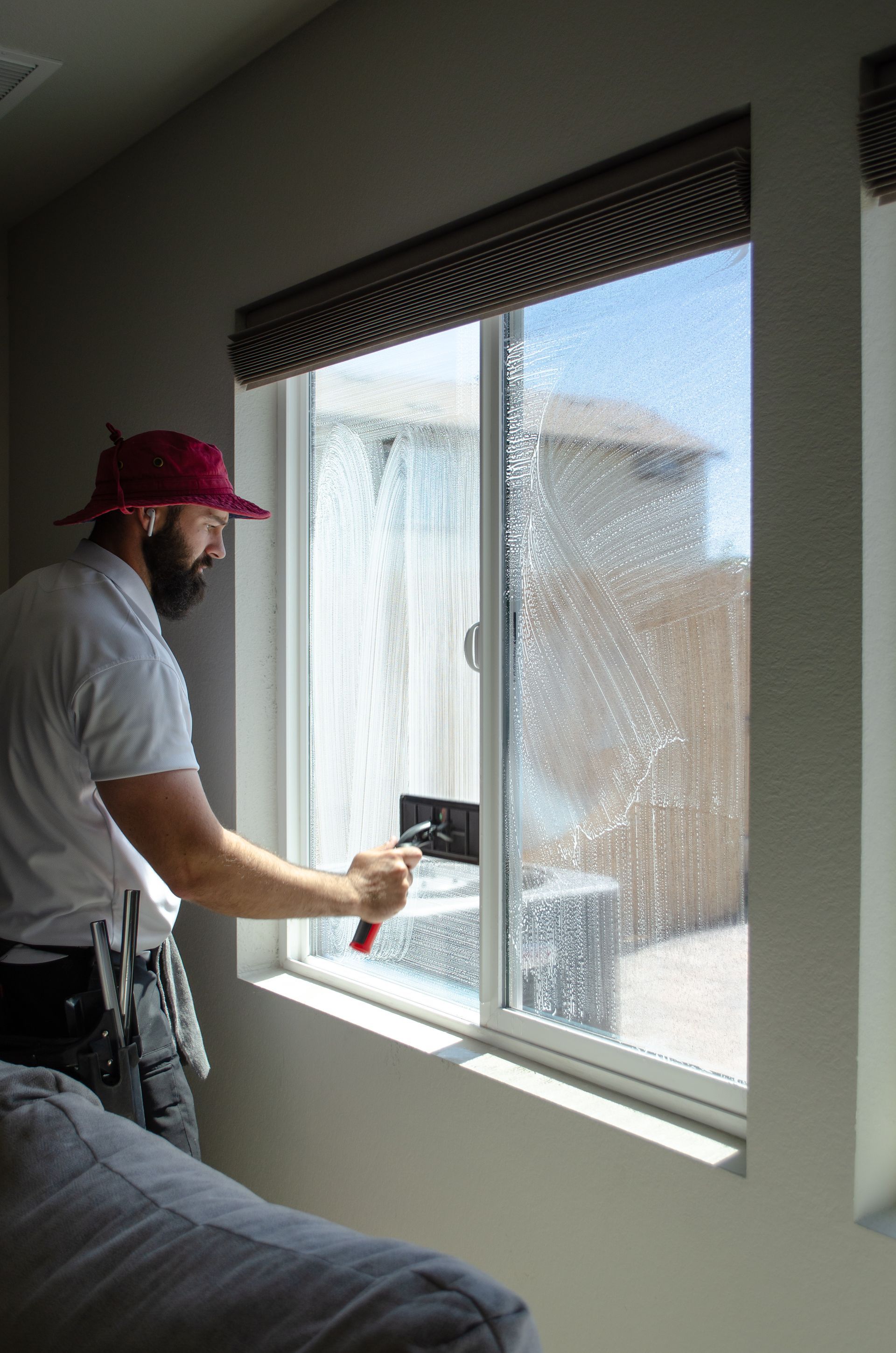 A man is cleaning a window in a living room.
