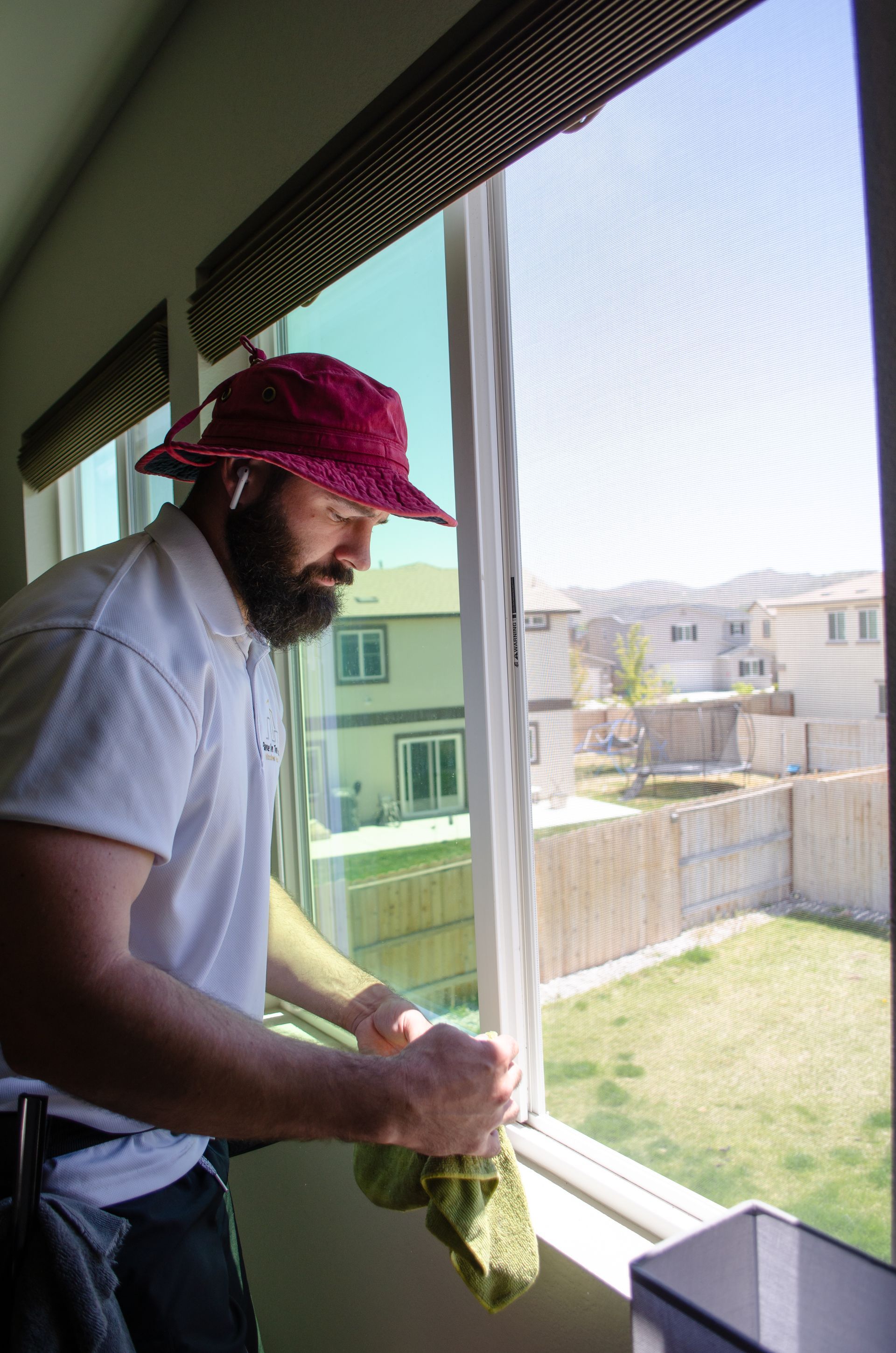 A man wearing a red hat is cleaning a window.