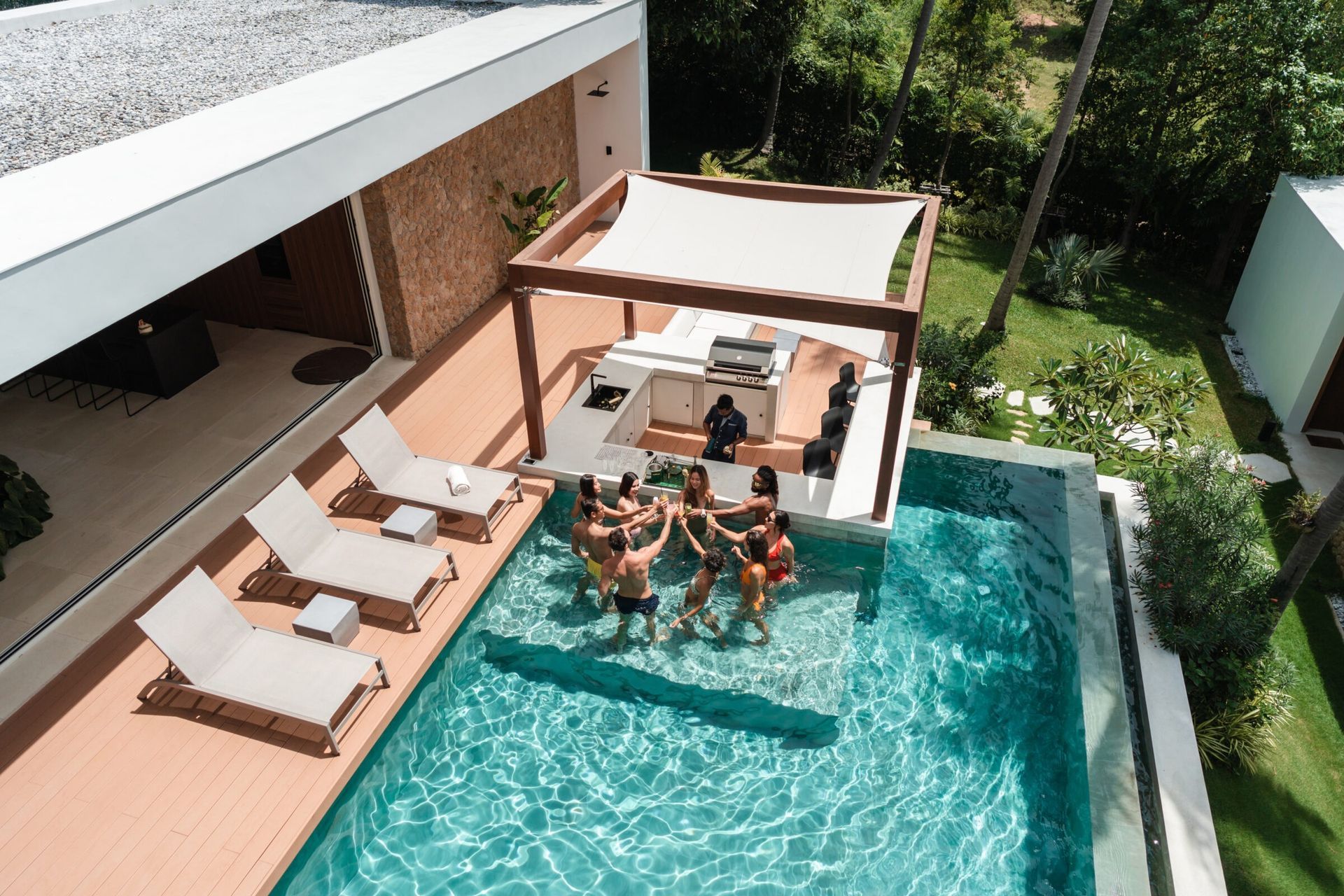 A pool with a cabana lounge area, with a group of people in the pool.