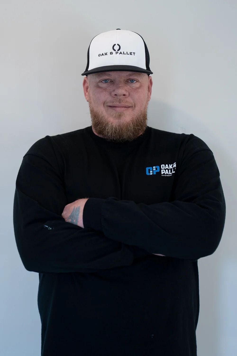 Man in black long sleeve shirt and baseball cap with arms crossed.