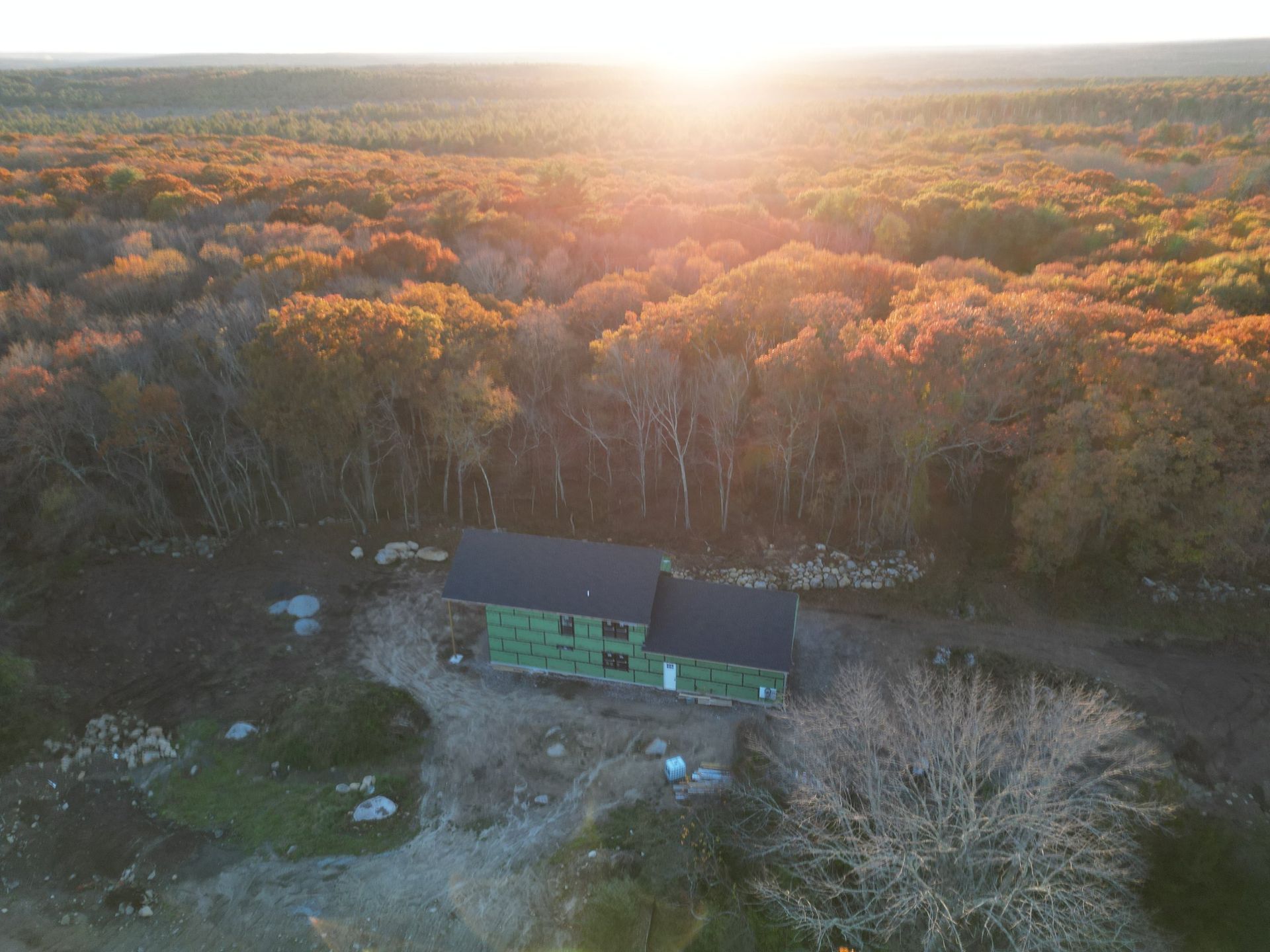 Aerial view of a house under construction in a forest. Autumn foliage with a bright sunset.