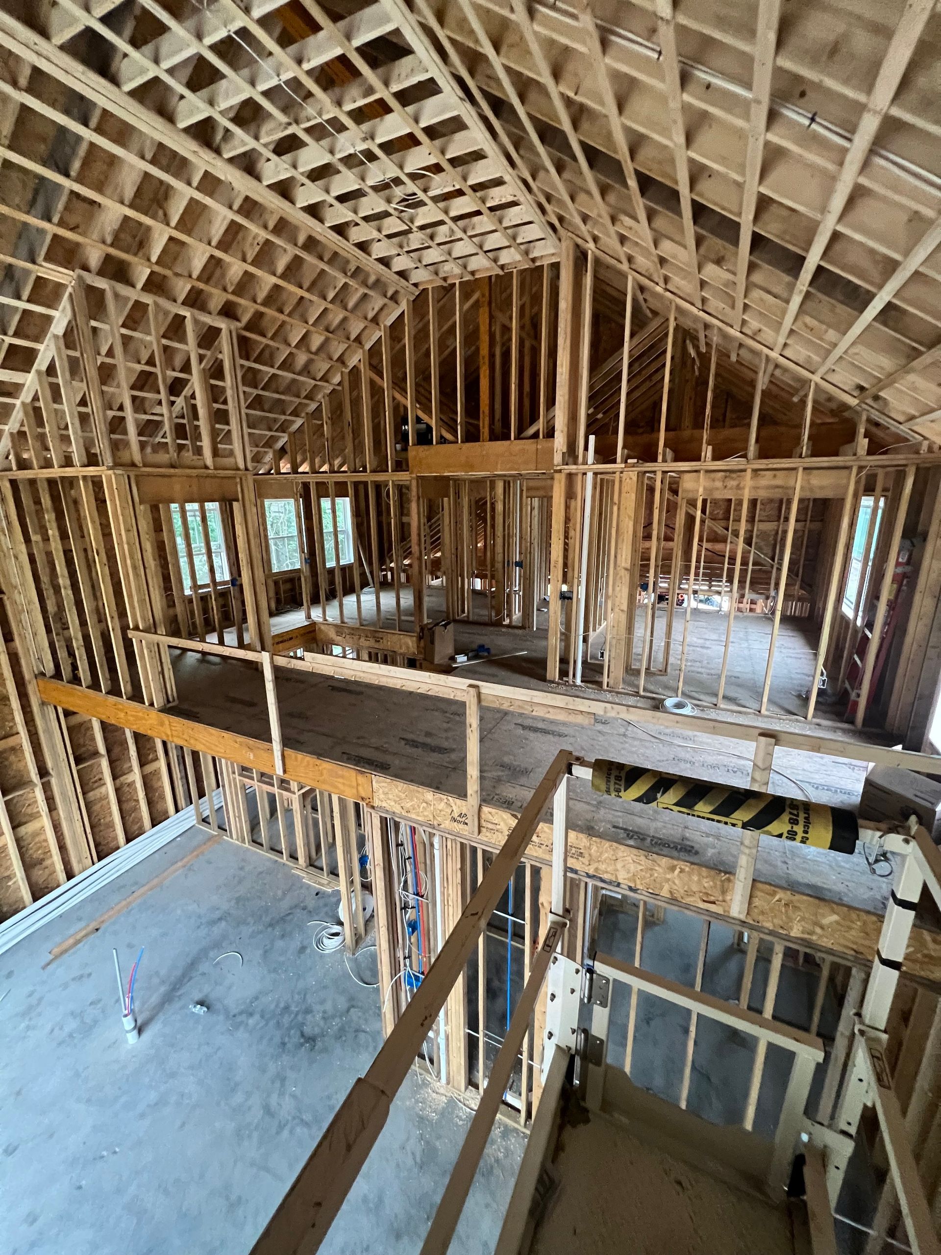 Interior of a house under construction. Wooden framing visible. Second floor balcony, concrete floor.