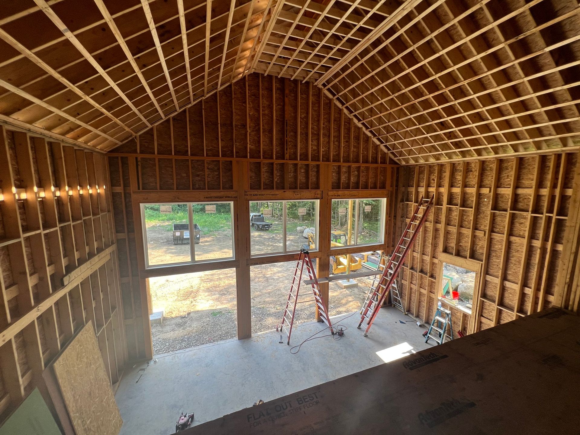 Interior framing of a building under construction, featuring large windows and an angled ceiling.