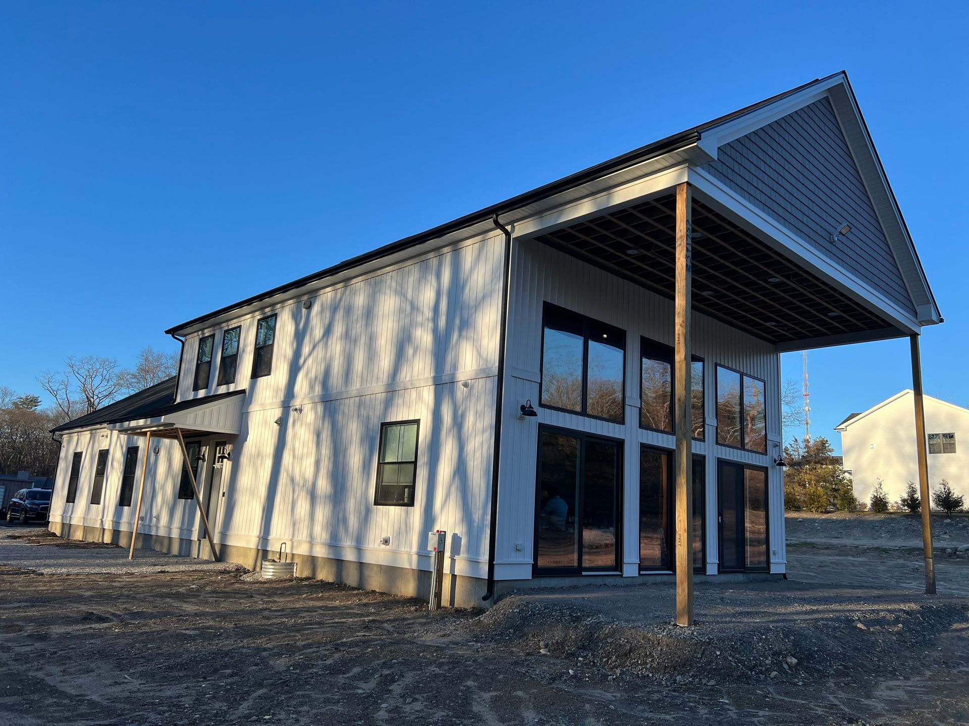 New building under construction with white siding, large windows, and a covered porch.