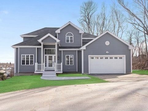 Gray house with white trim, arched window, and two-car garage. Front lawn and driveway visible.