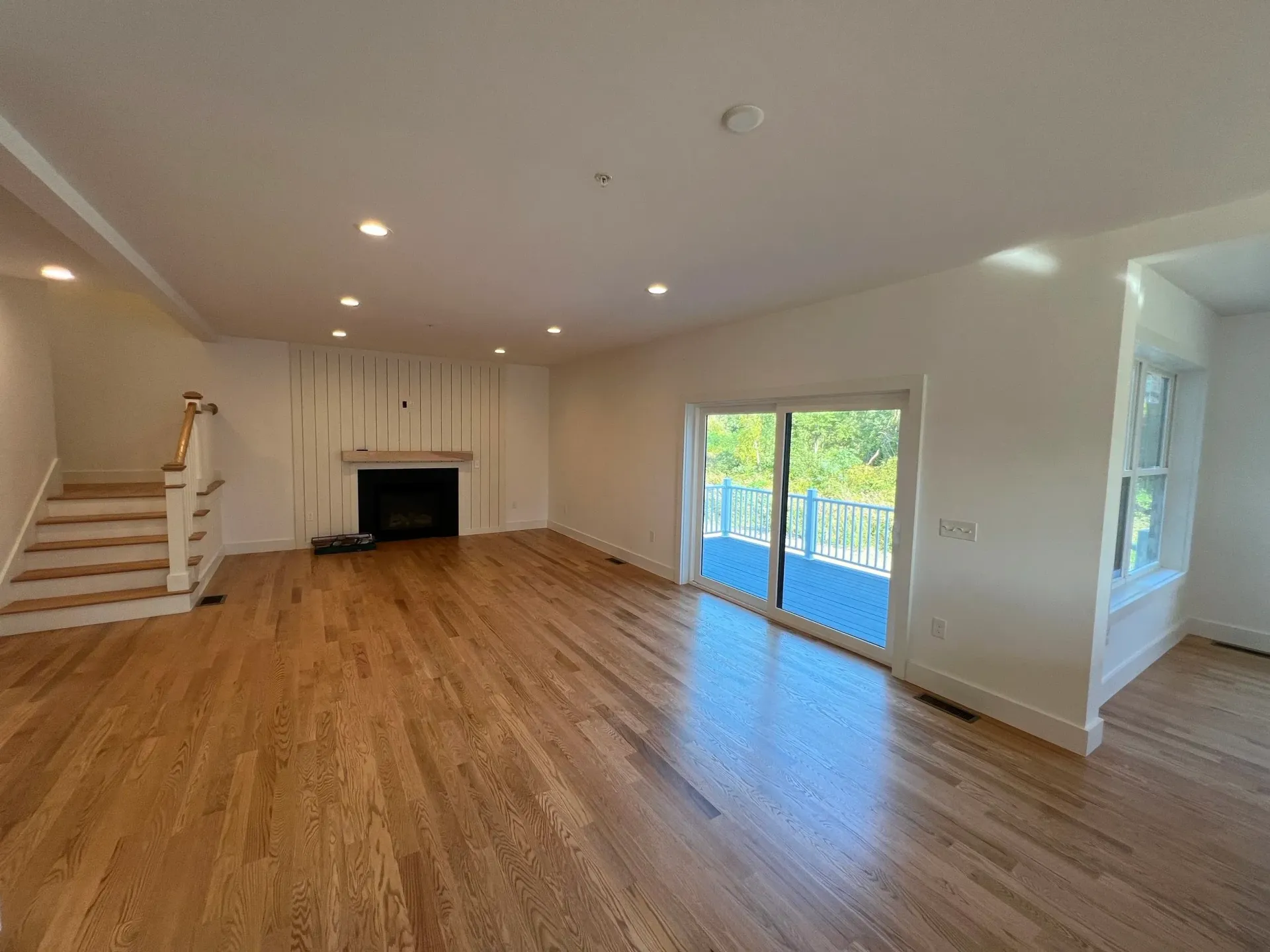 Empty living room with wood floors, fireplace, and sliding door to a balcony.