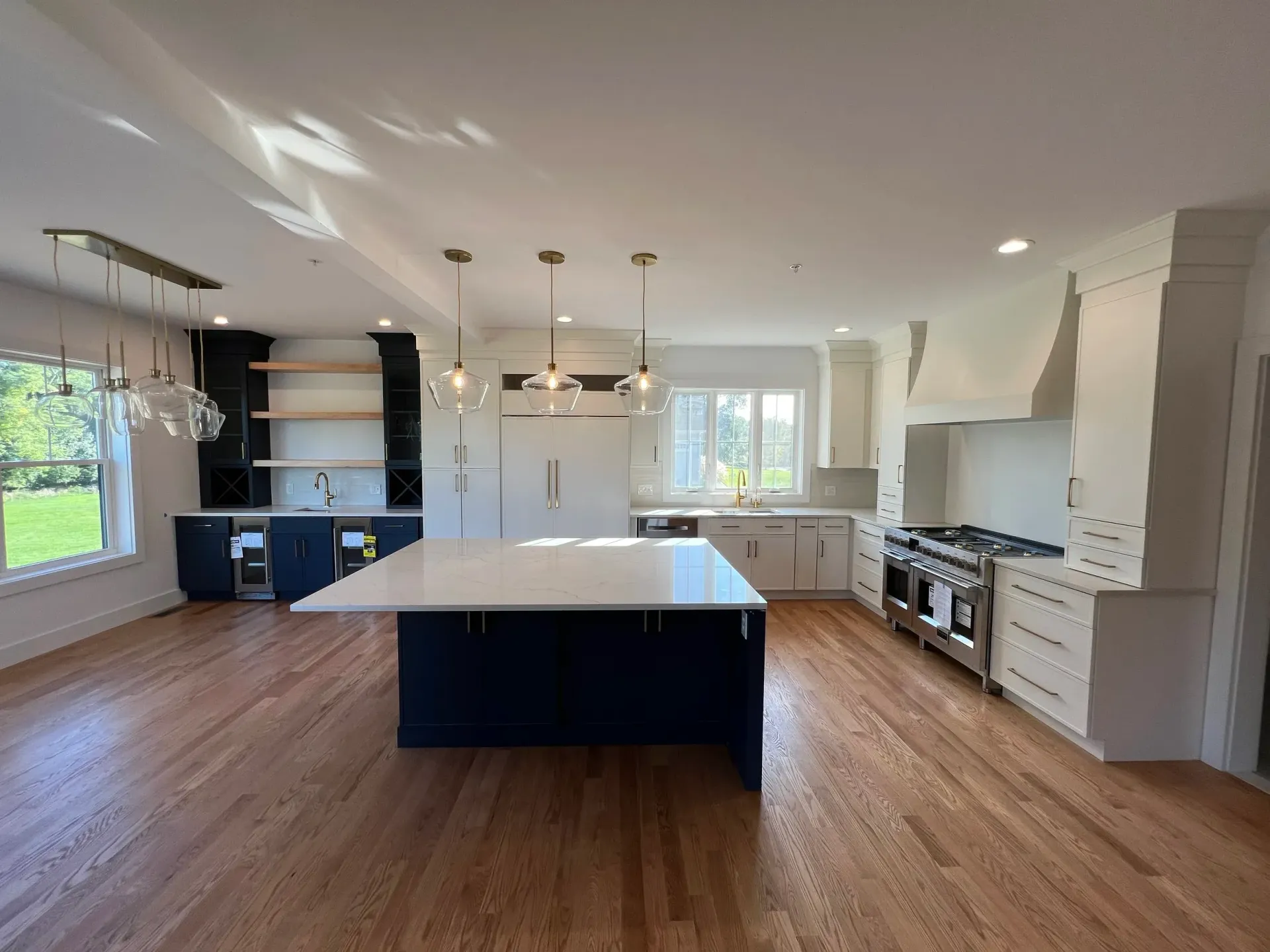 Spacious, modern kitchen with hardwood floors, white cabinets, and a blue island.