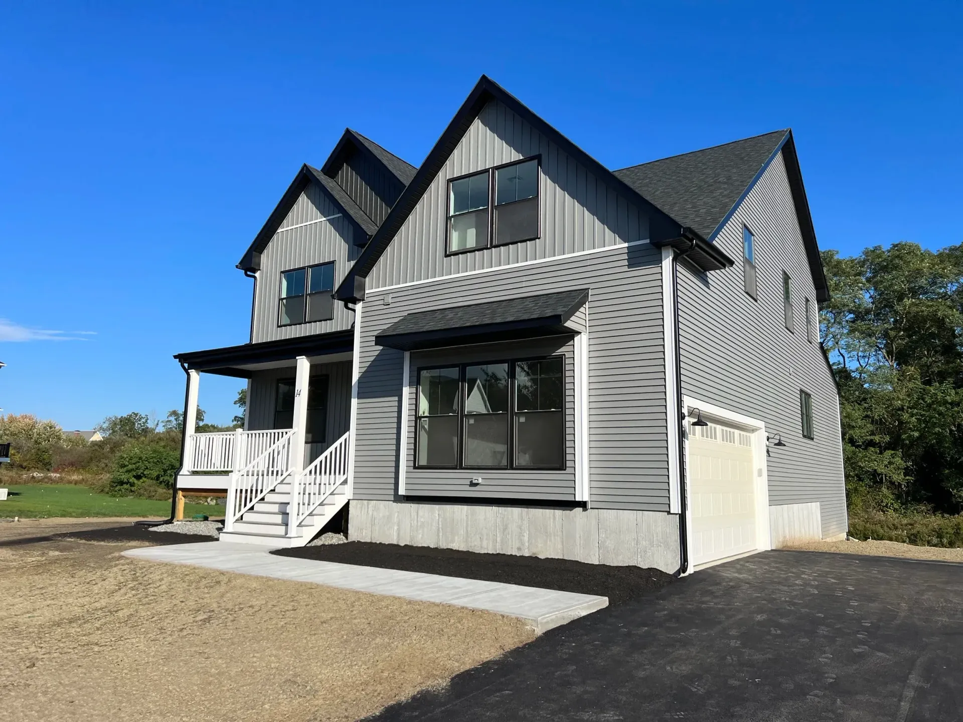 Modern gray house with black accents and a small porch on a bright, sunny day.