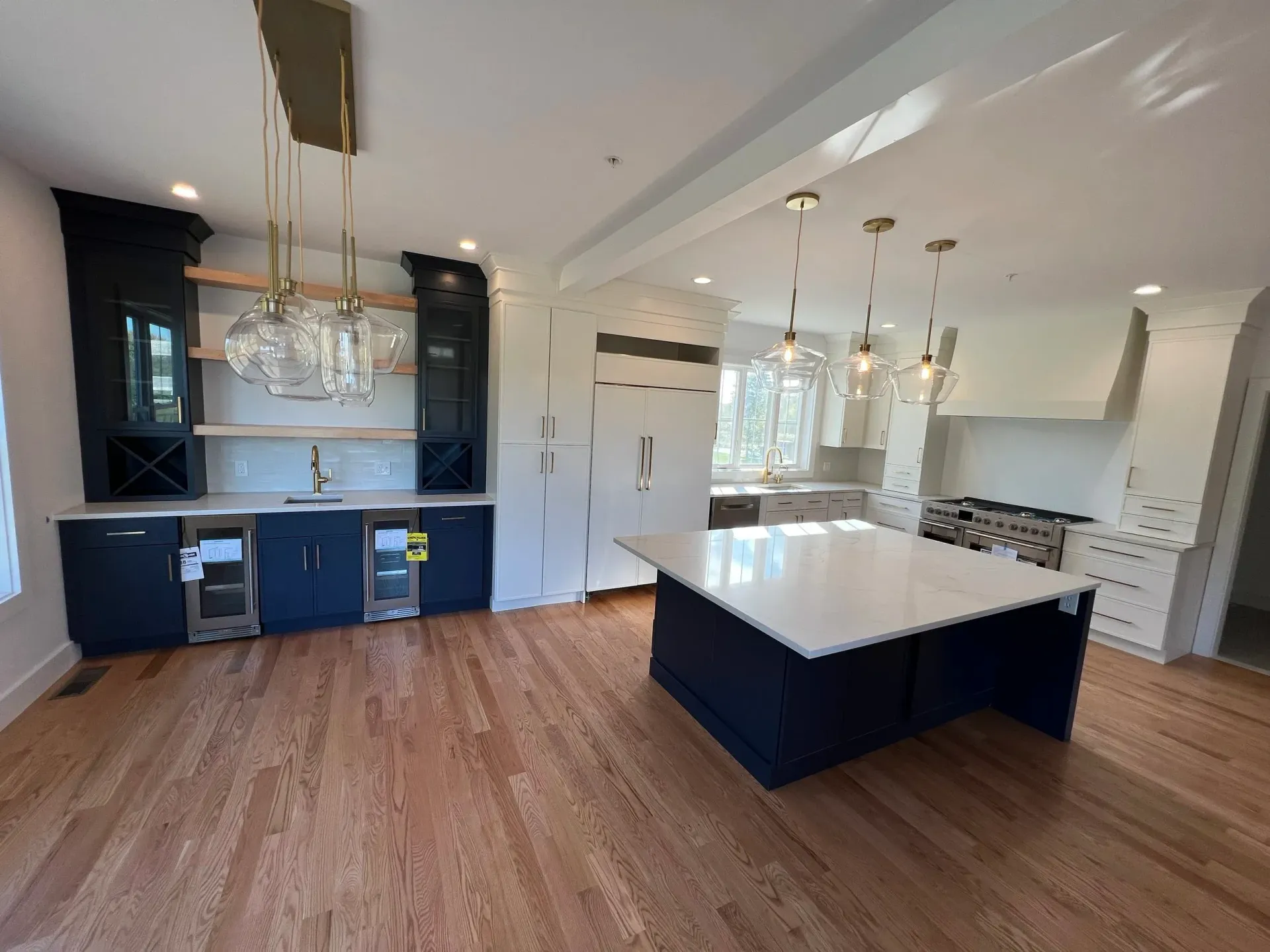A newly renovated kitchen with navy and white cabinets, a large island, and wood floors.