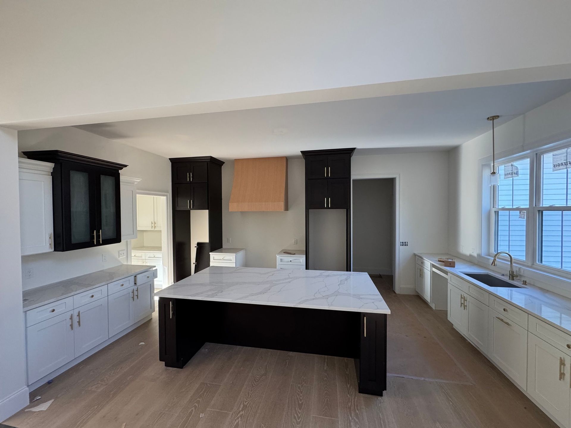 A nearly finished kitchen with dark and white cabinets, an island, and a window.