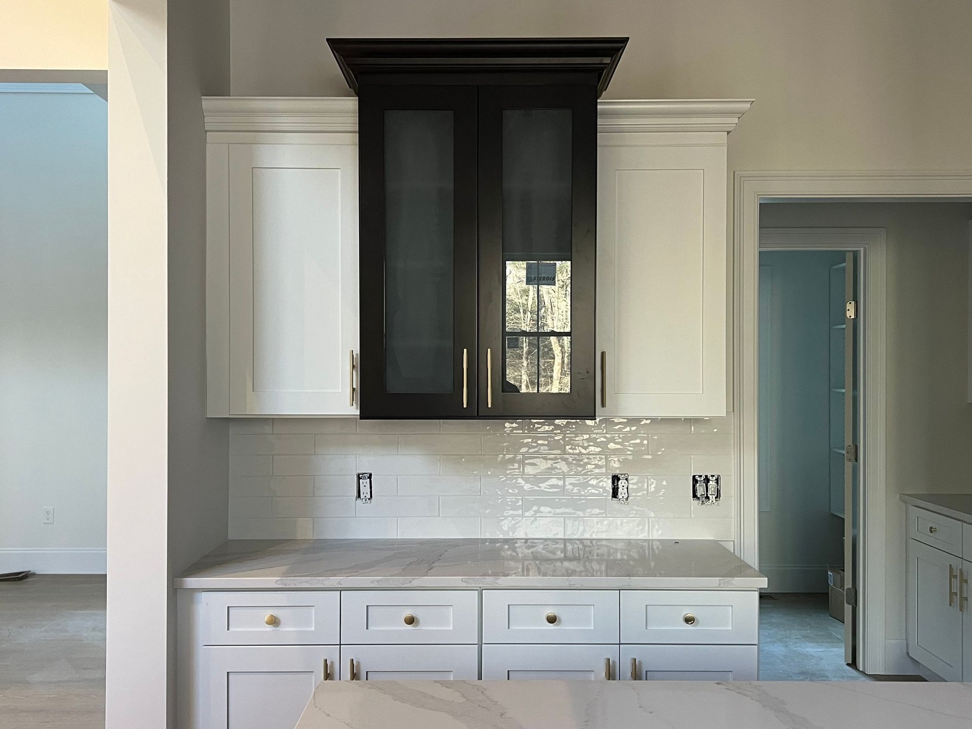White and black kitchen cabinets with marble countertop and subway tile backsplash.