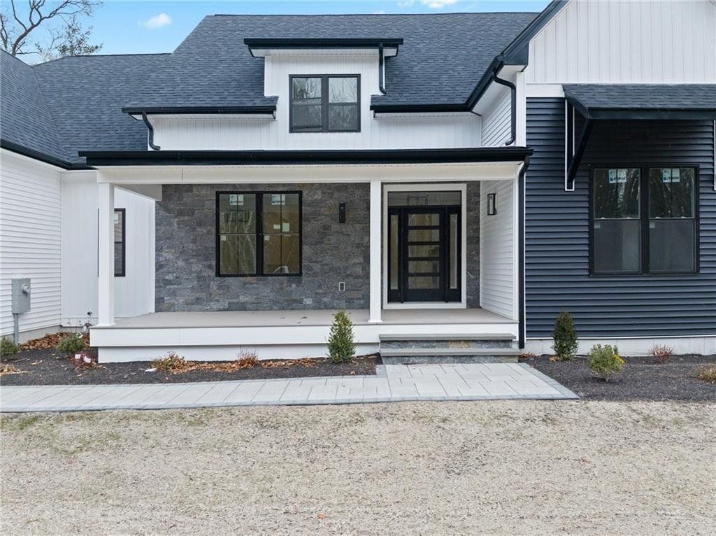 Modern farmhouse exterior with white siding, black trim, and gray stone porch.