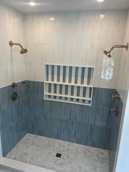 Blue and white tiled shower with dual shower heads and built-in shelf.