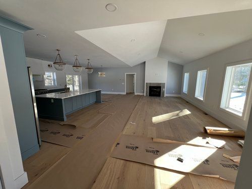 Interior of a new home with hardwood floors, kitchen island, fireplace, and large windows.