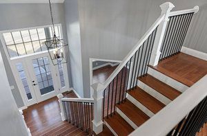 Staircase with wooden steps and black railings, leading to a front door with glass panels.