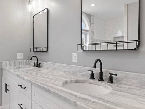 Bathroom with white cabinets, gray marble countertop, black fixtures, and mirrors.