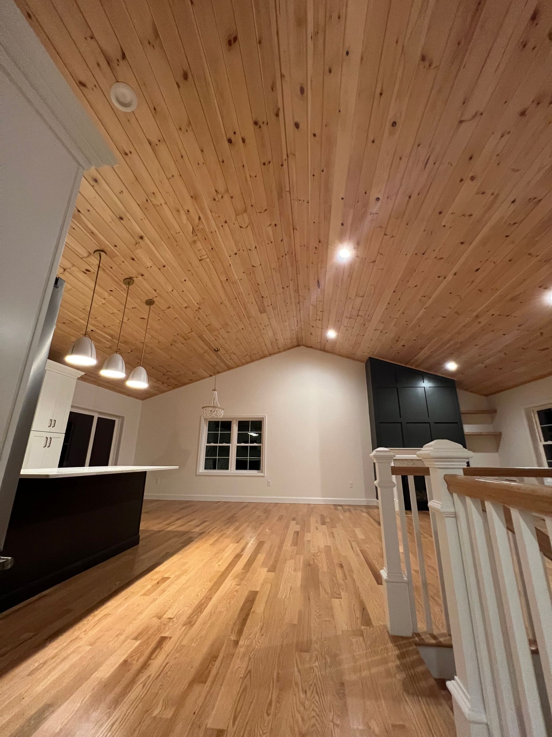 Interior view of a modern home with a wooden ceiling and hardwood floors; white walls and accents.
