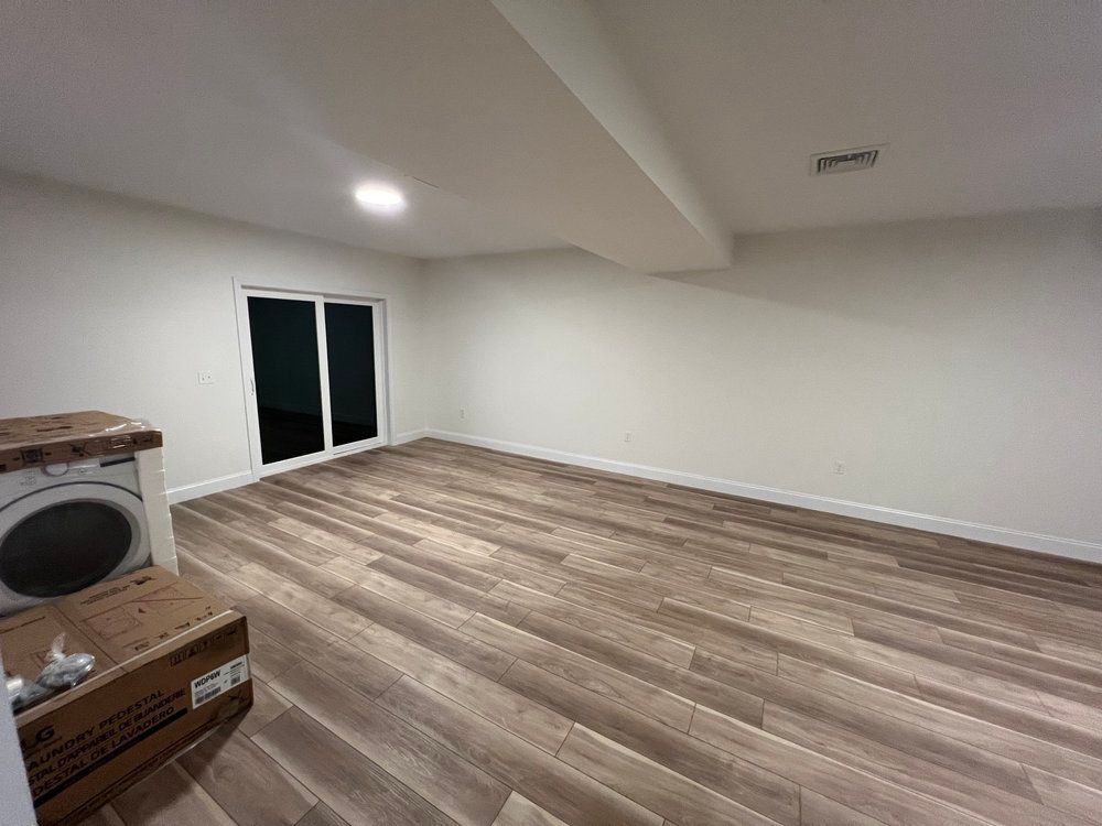 Empty room with wood-look flooring, white walls, and sliding glass door. A washing machine is on the left.