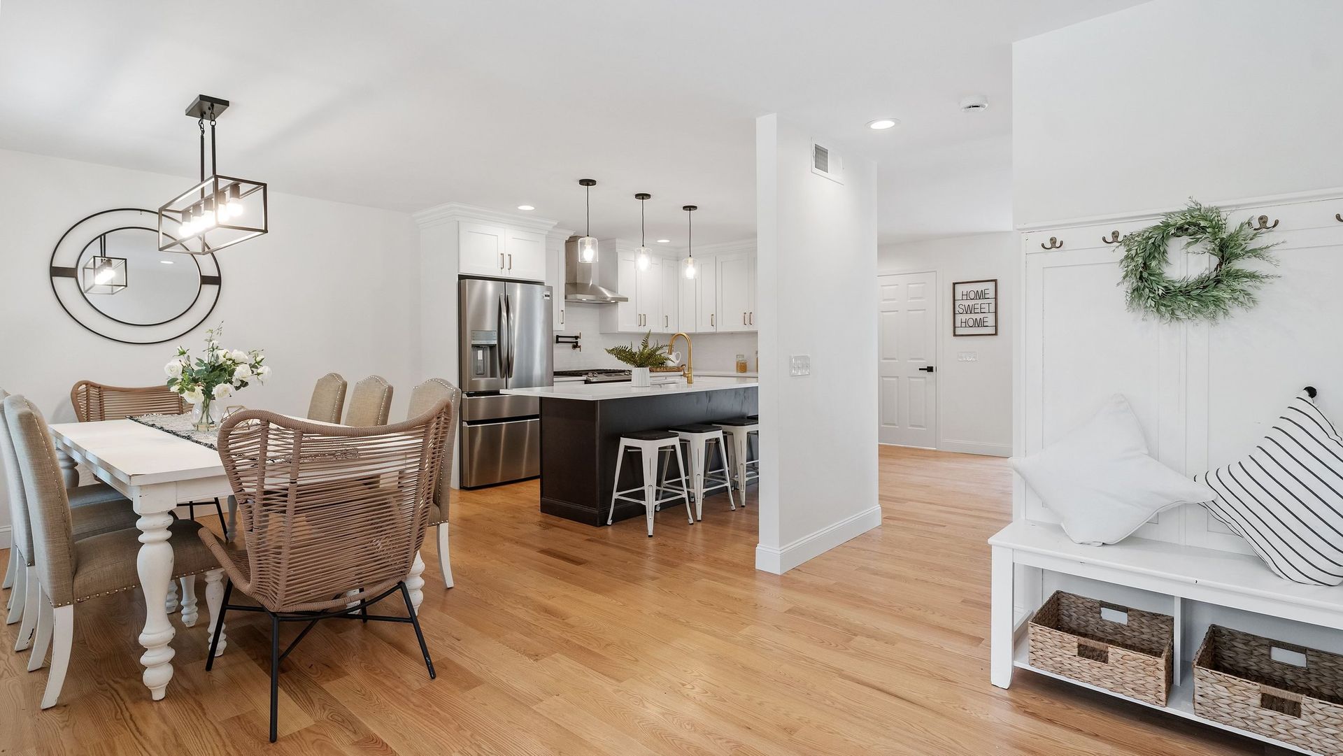 Bright, open-concept home with dining table, kitchen island, and entry bench with wreath.