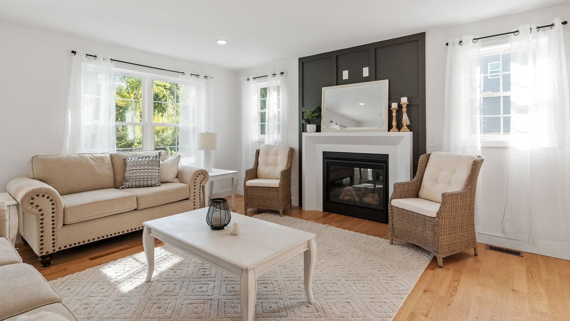 Living room with white walls, fireplace, sofa, and two wicker armchairs.