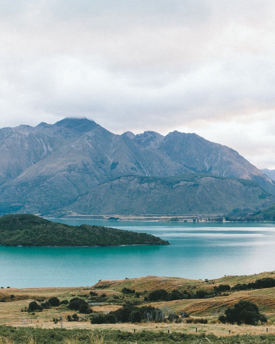 Lake and mountain landscape with turquoise water and cloudy sky.