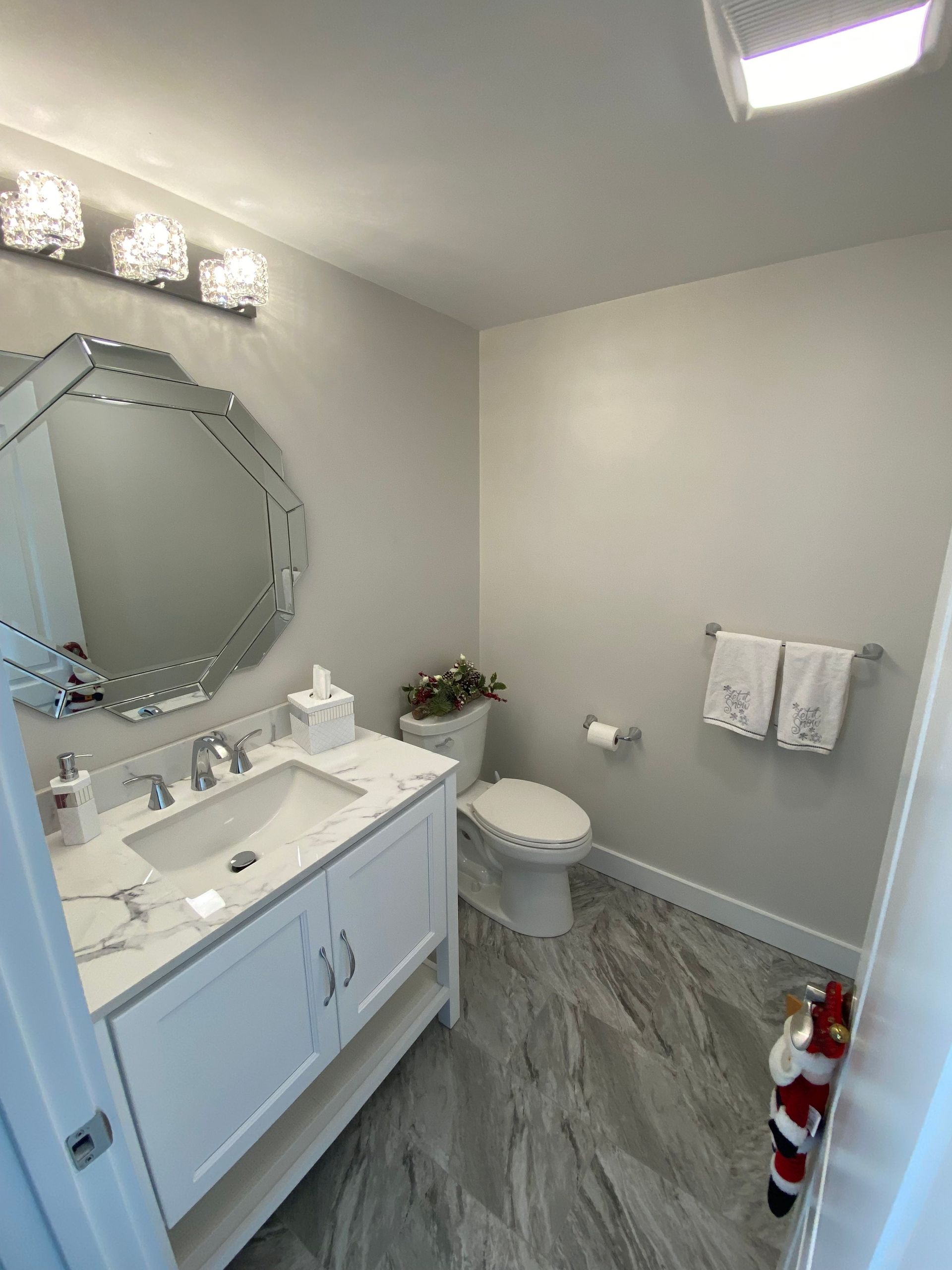 Bathroom with white vanity, ornate mirror, toilet, and gray flooring.