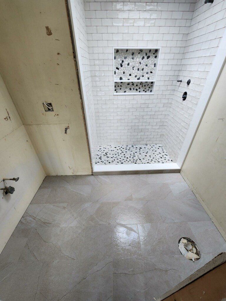 Bathroom under construction with tiled shower and concrete floor.