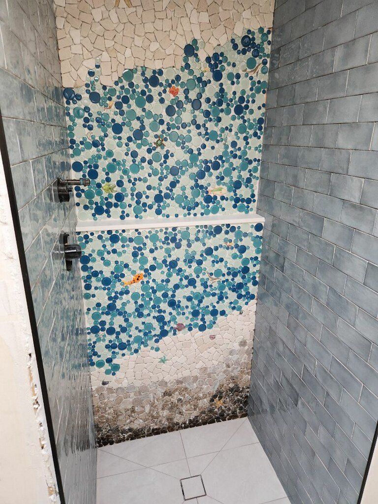 Shower interior with mosaic tile wall and gray tiled walls.