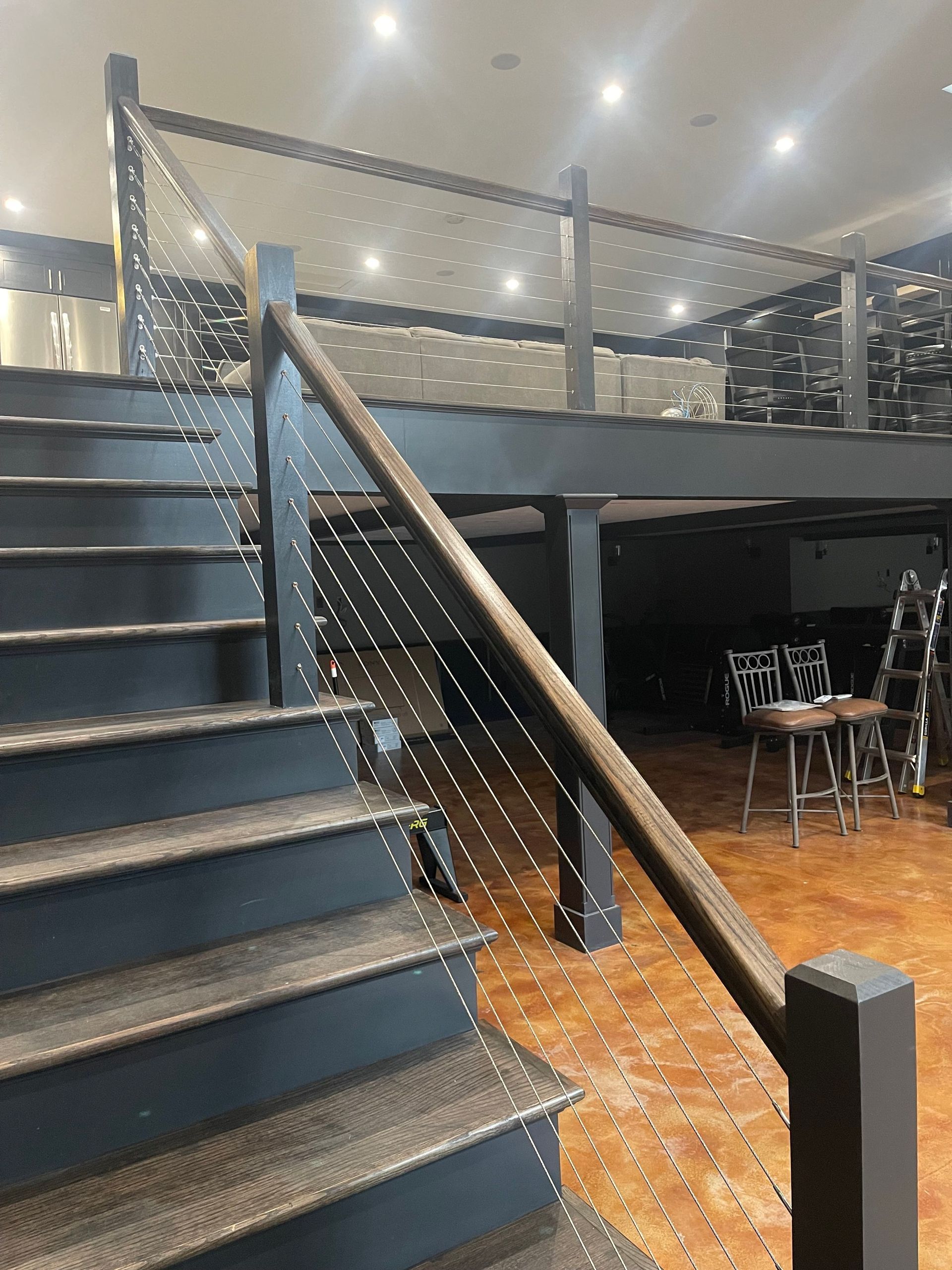 Staircase with cable railing and dark wood accents. Leads to a loft area.
