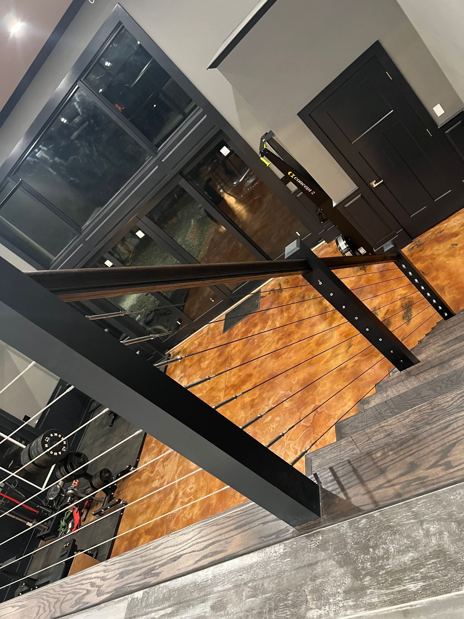 Staircase with wooden steps and a black metal railing. Dark wood door and windows above.