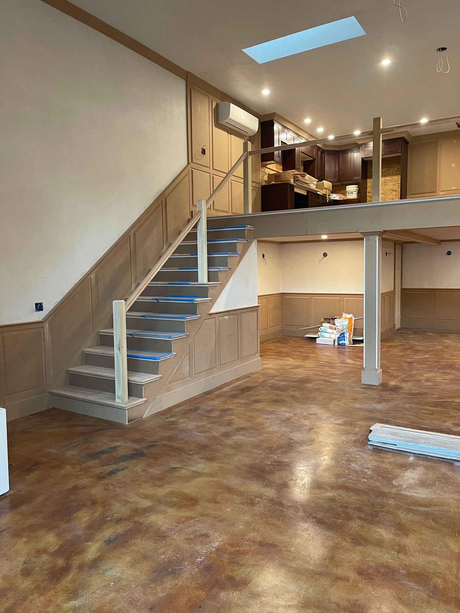 Staircase leading to a raised level with finished wood trim and a stained concrete floor in a room.