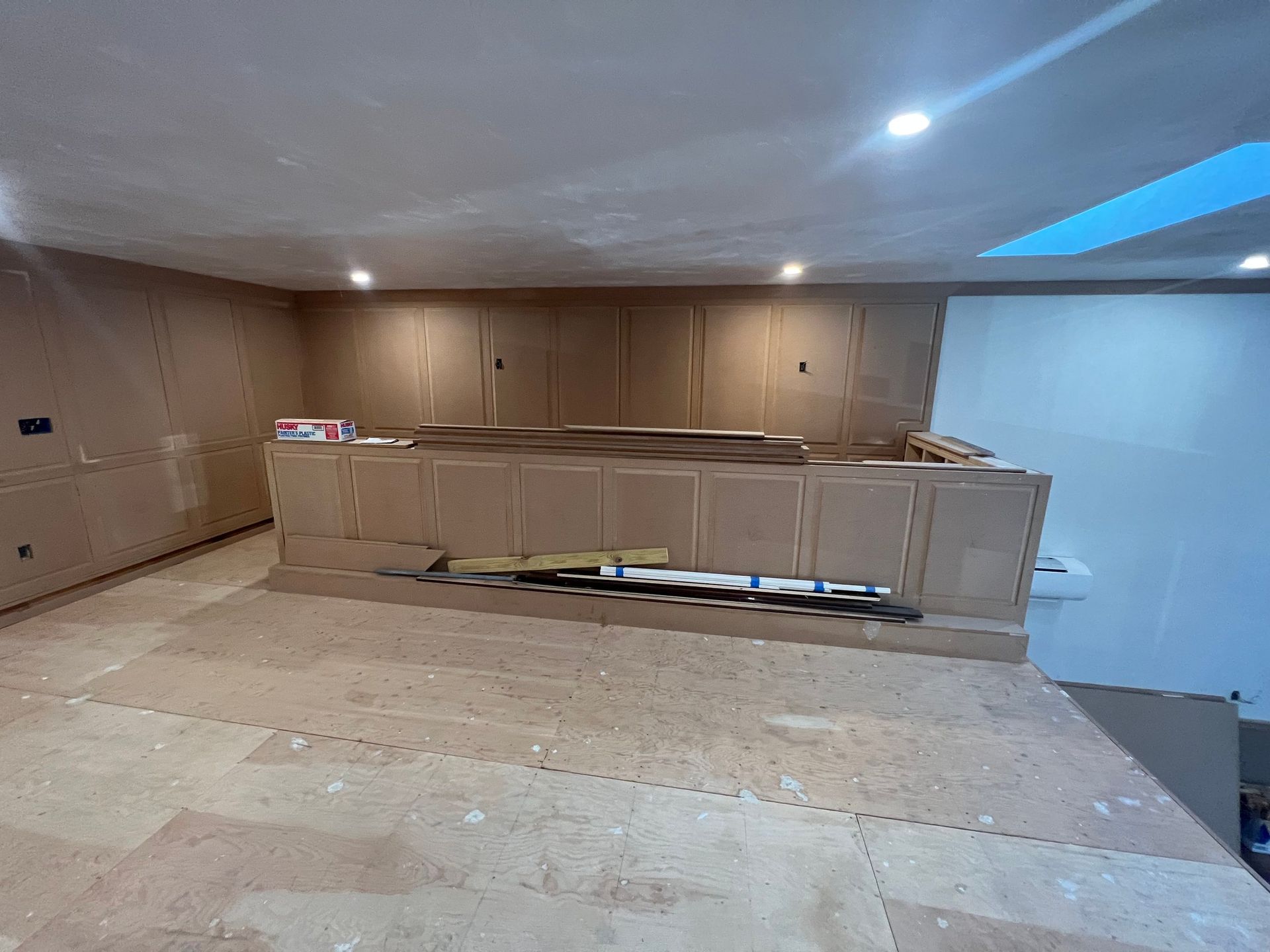 Interior under construction with a bar and skylight. Beige walls, exposed flooring, and construction materials.