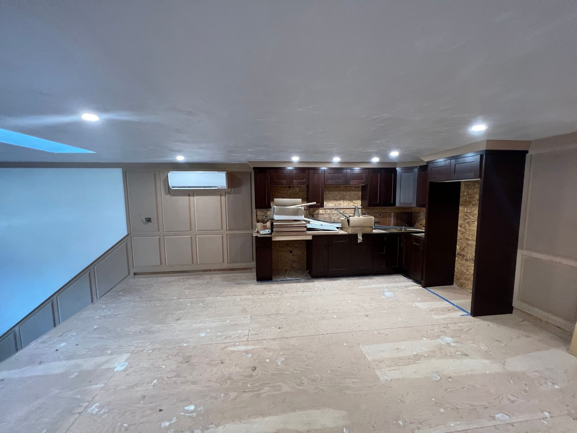 Basement under construction with dark cabinets, white walls, and exposed flooring.