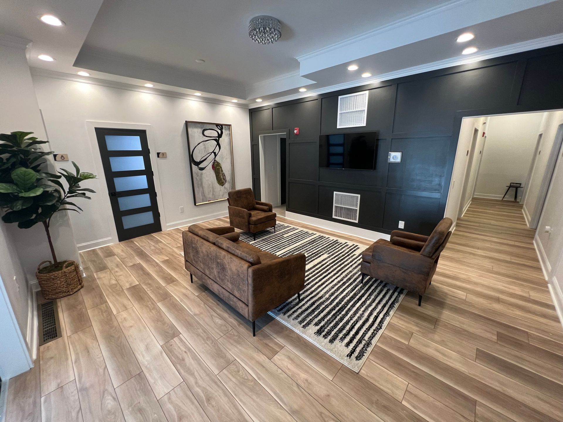 Modern waiting area with brown seating, black accent wall, and wood flooring.