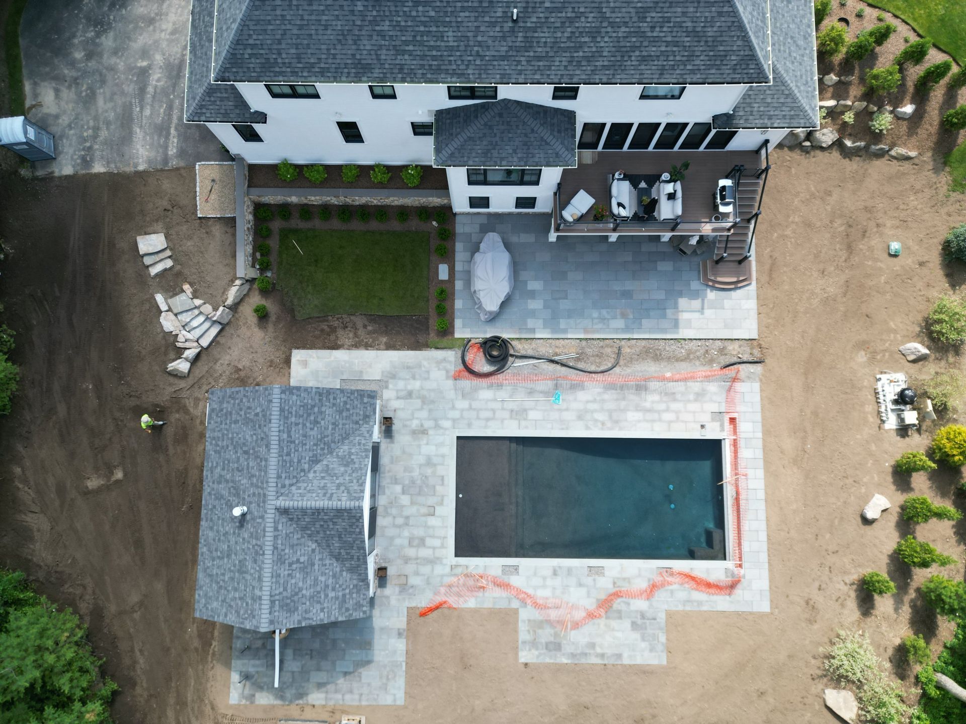 Overhead view of a house with a pool, patio, and cabana under construction in a yard.