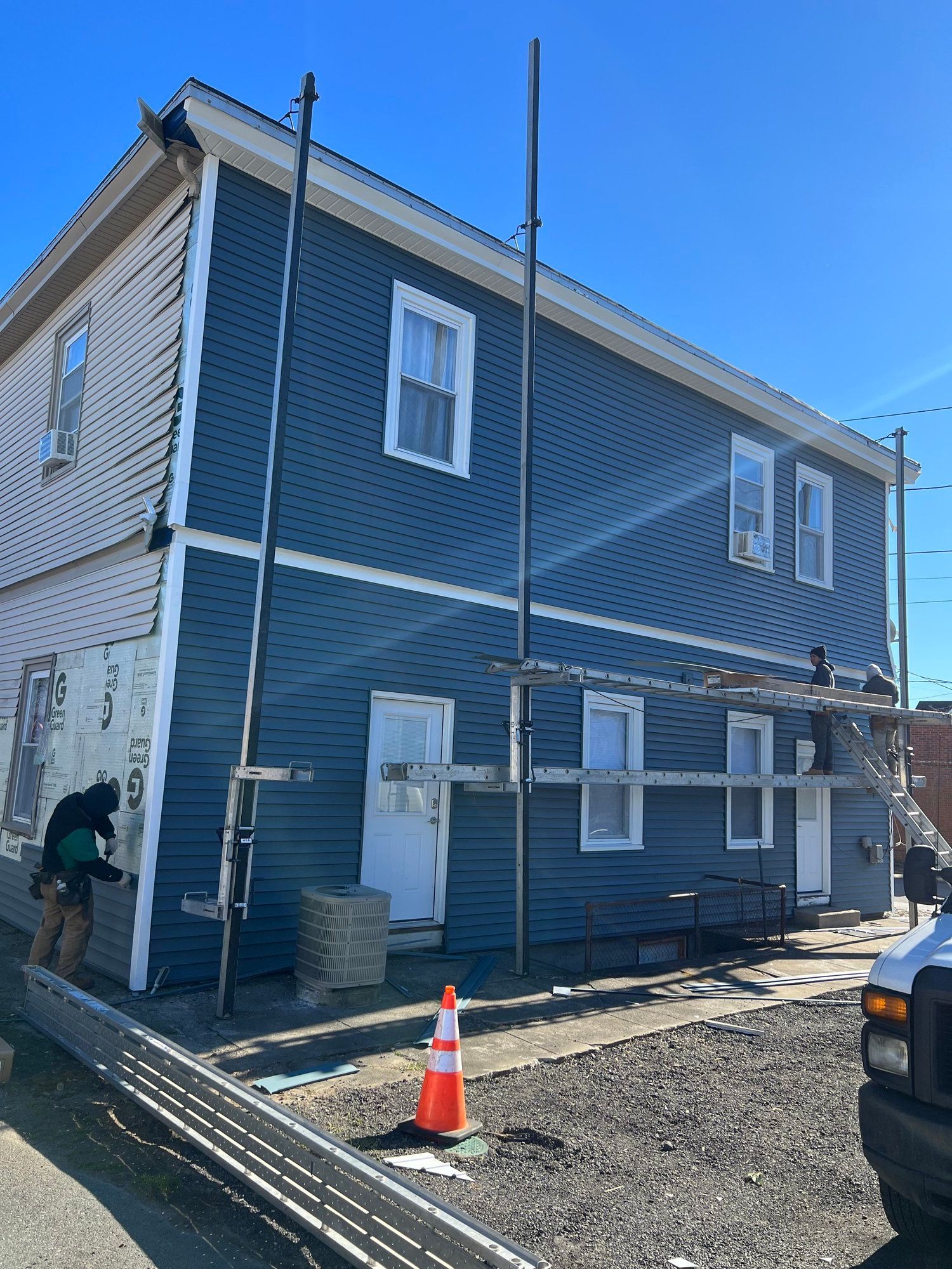 Blue and white building under construction with scaffolding and workers.