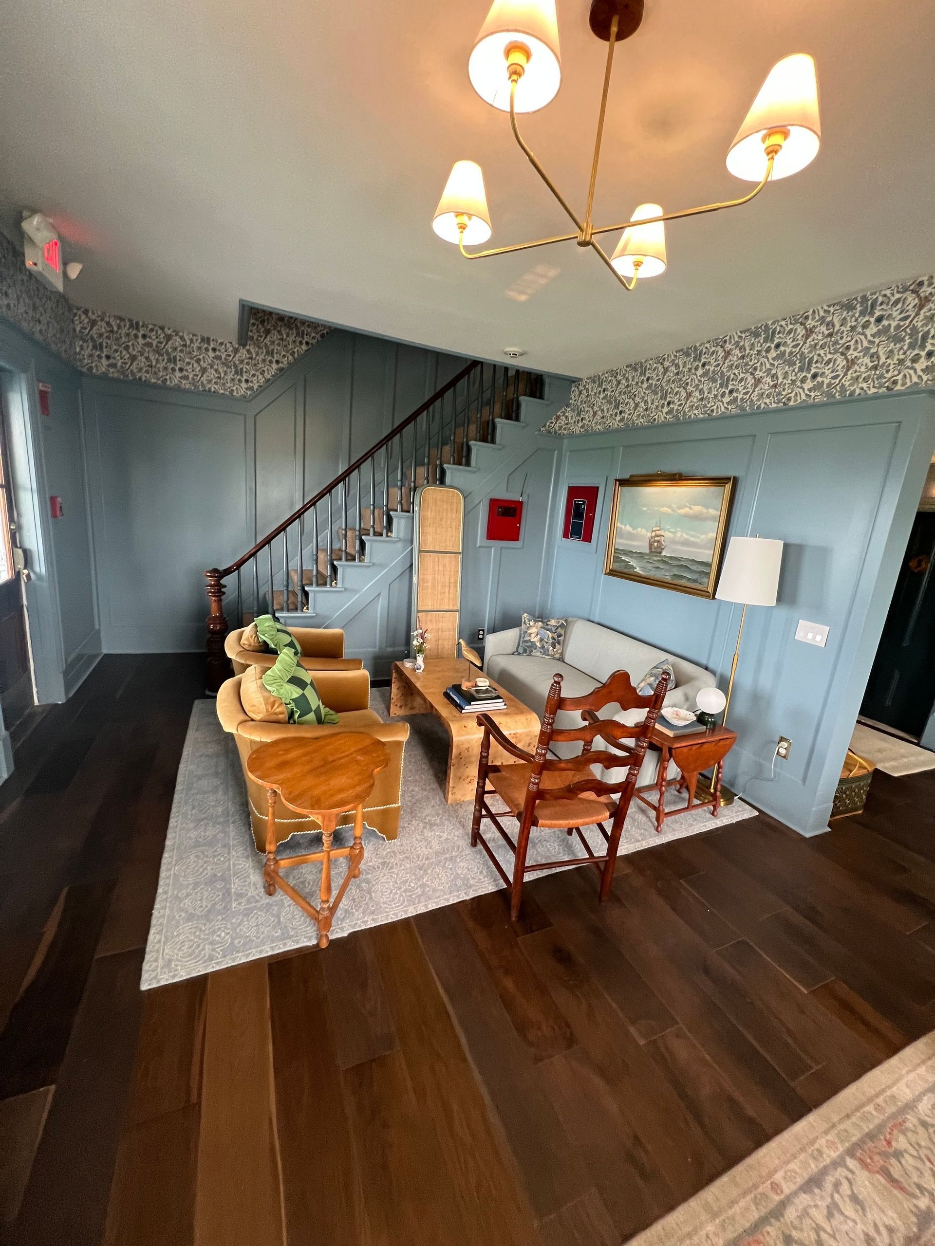 Living room with blue walls, stairs, seating, and a chandelier.
