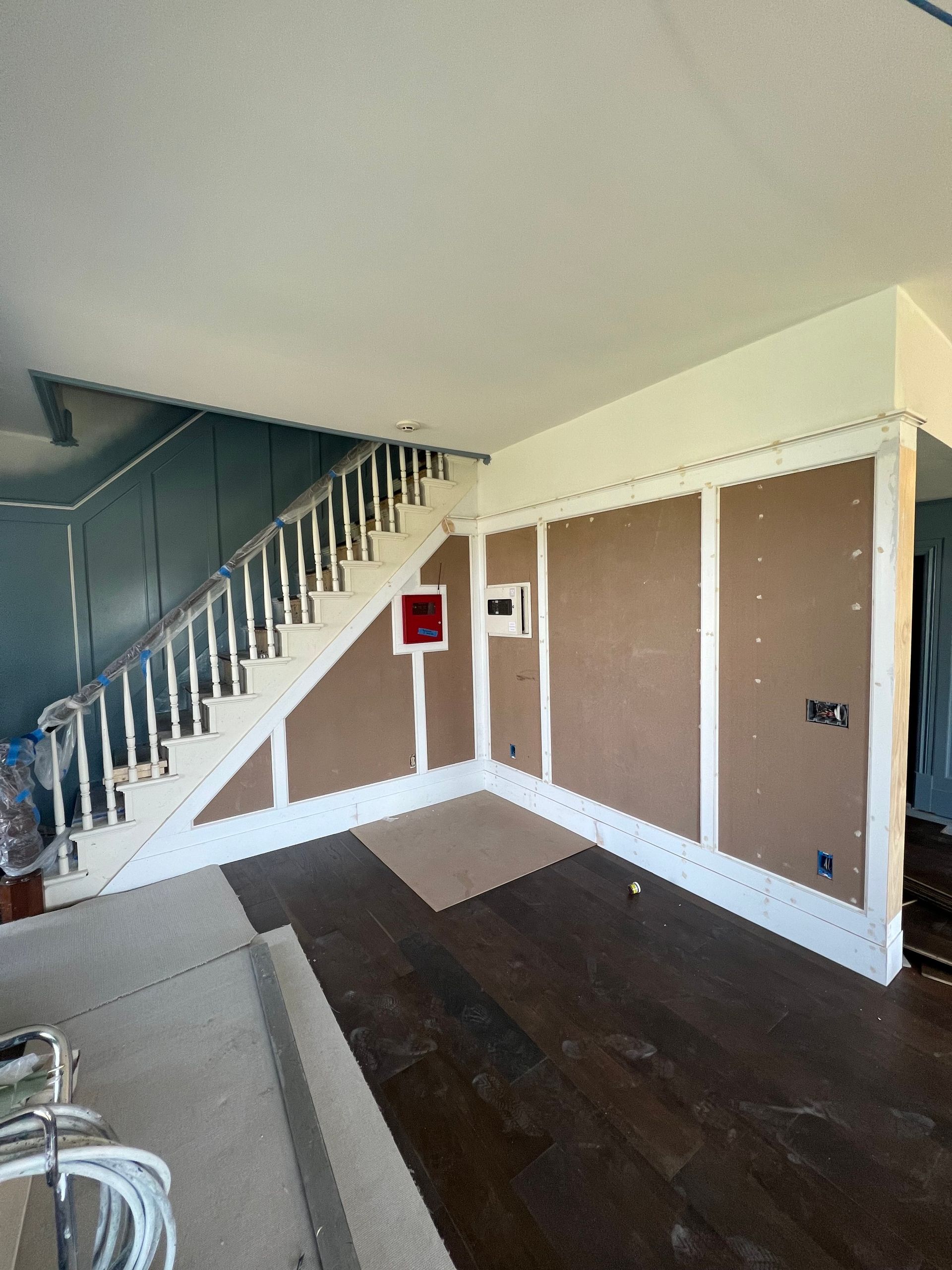 Interior construction with a staircase, unfinished walls, and wood flooring.