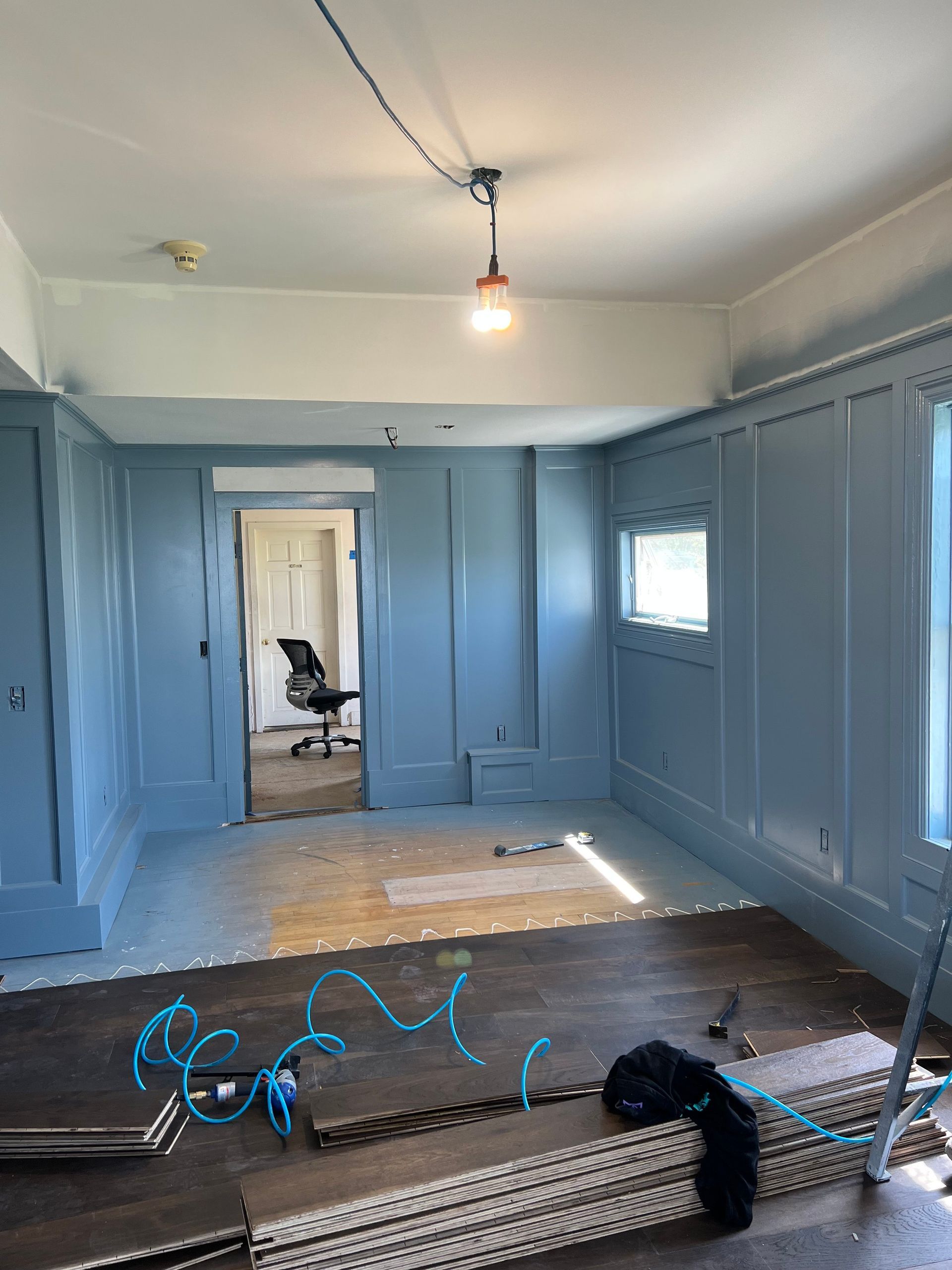Room under renovation; blue walls, white ceiling, new flooring partially installed.