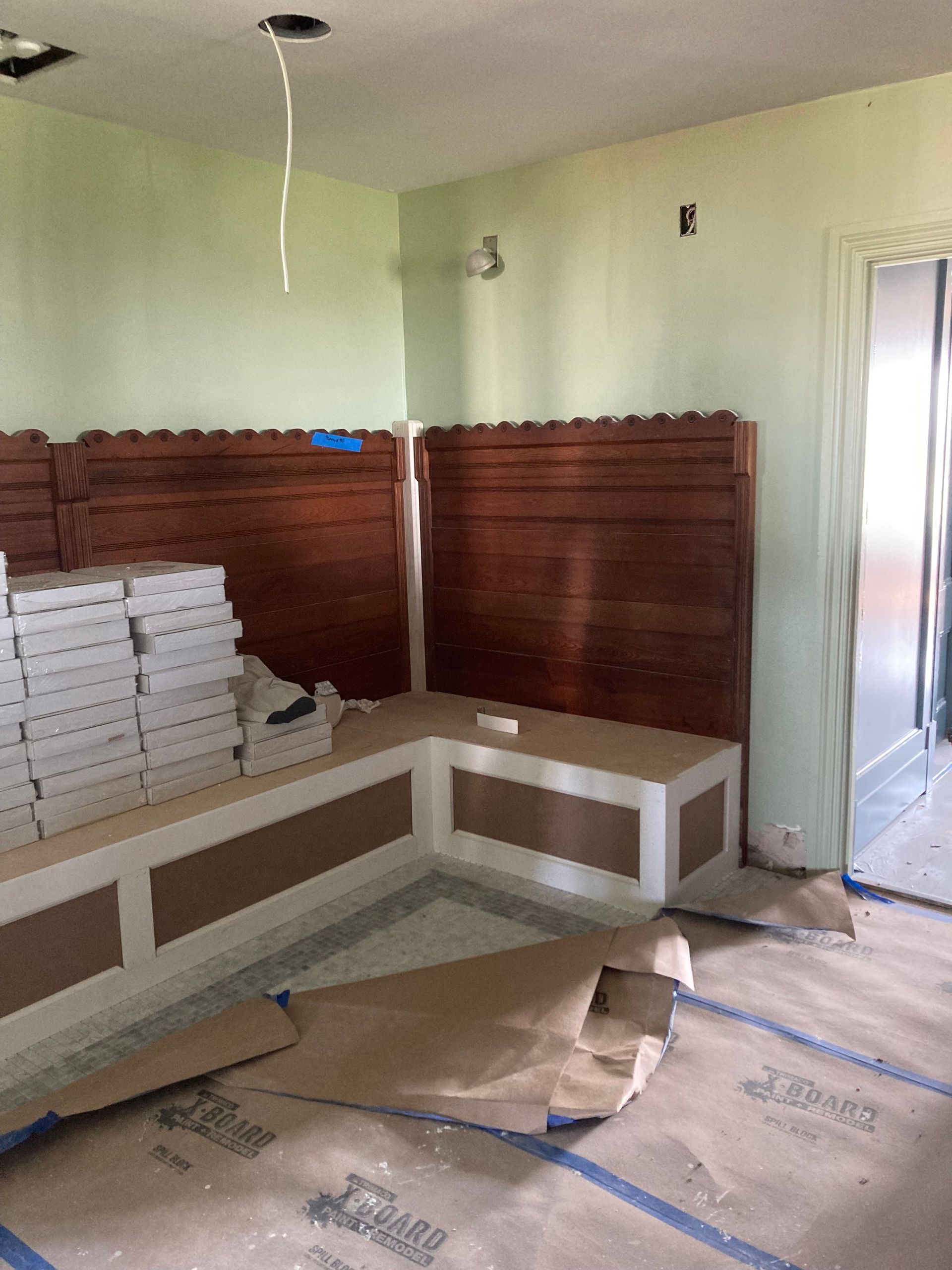 Built-in wooden bench with brown headboards and white and brown trim. Construction zone with pale green walls.