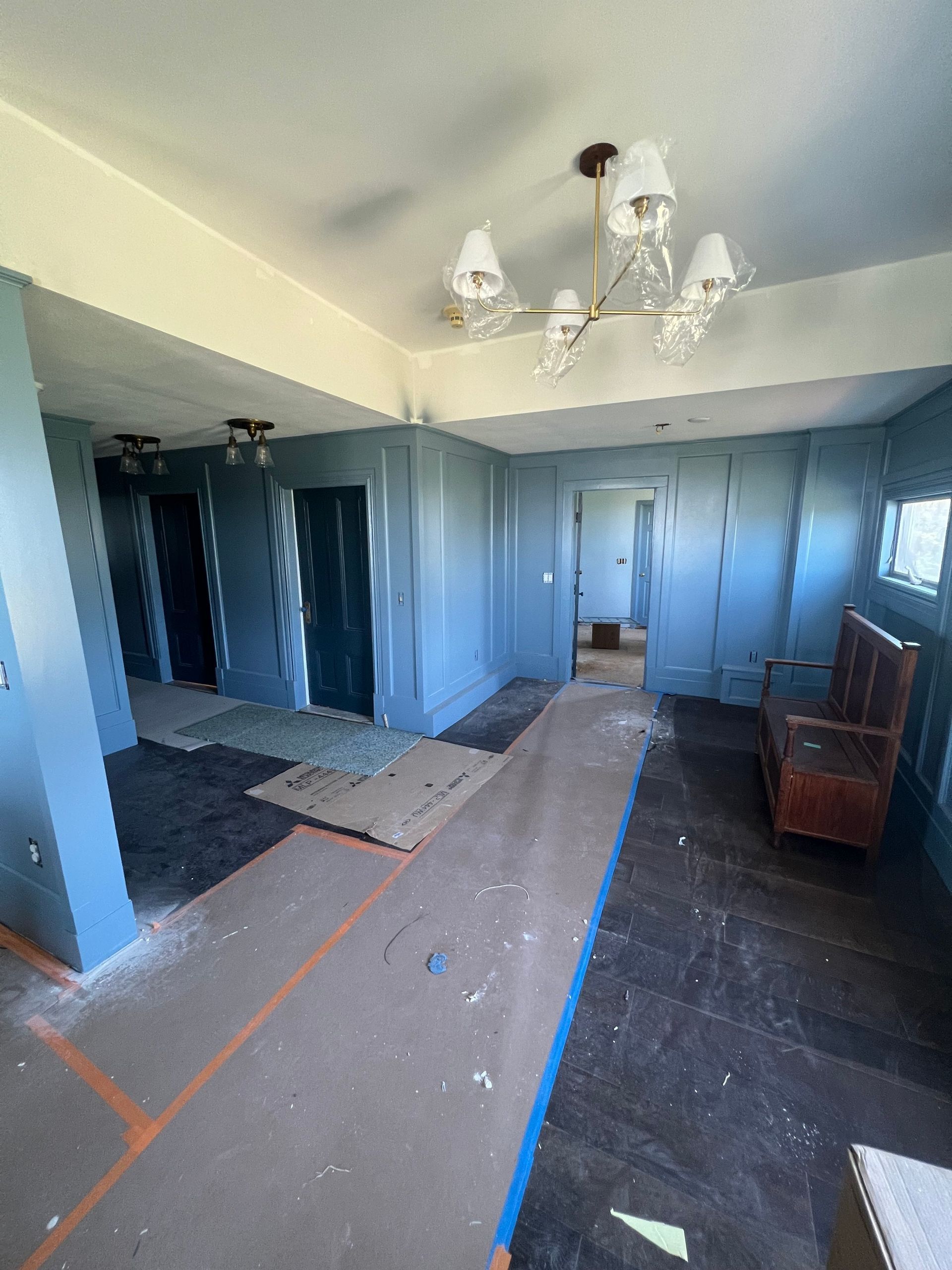 Room under construction with blue walls, dark flooring, and a chandelier.