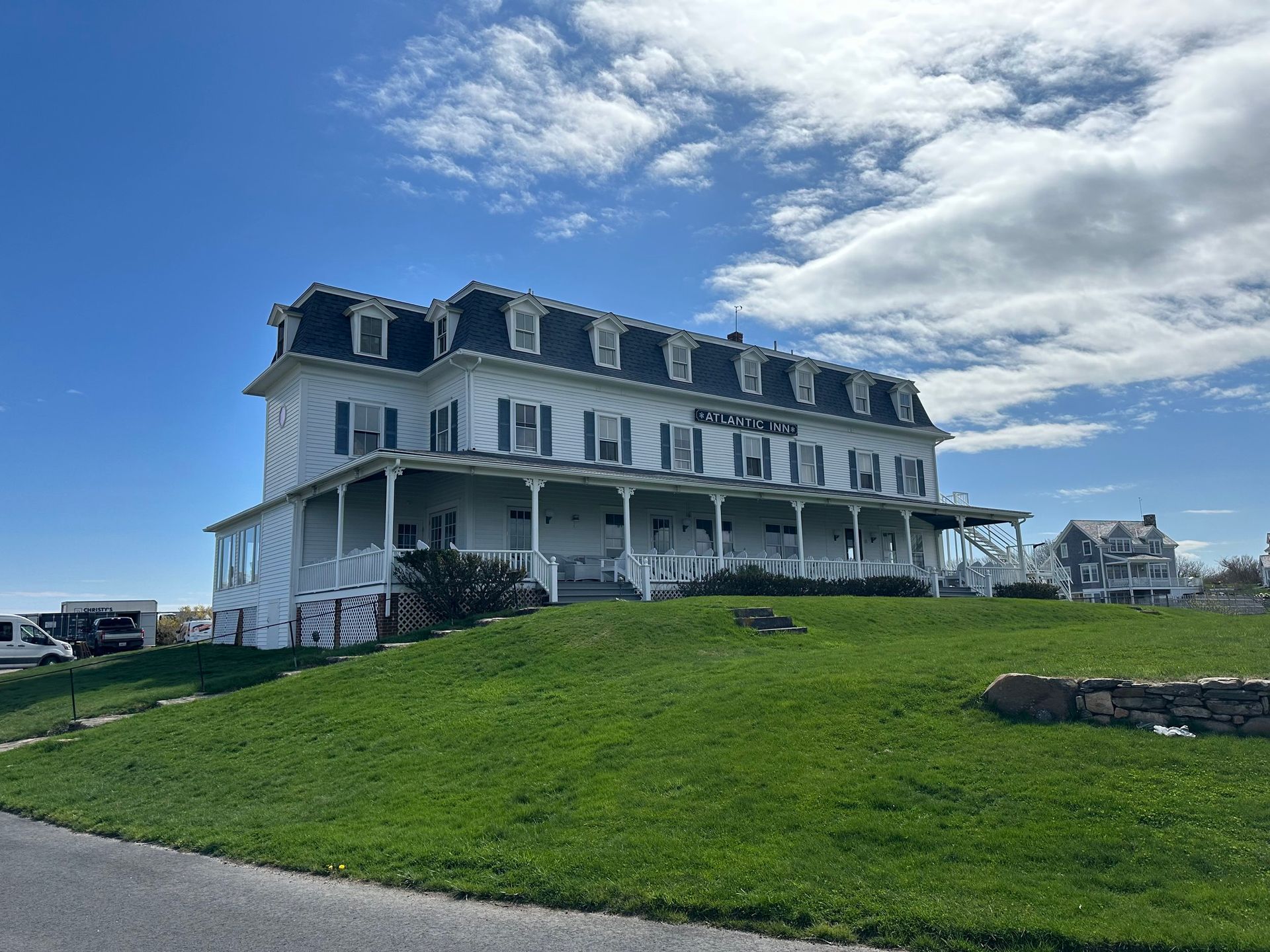 White Victorian-style building on a grassy hill under a partly cloudy sky.