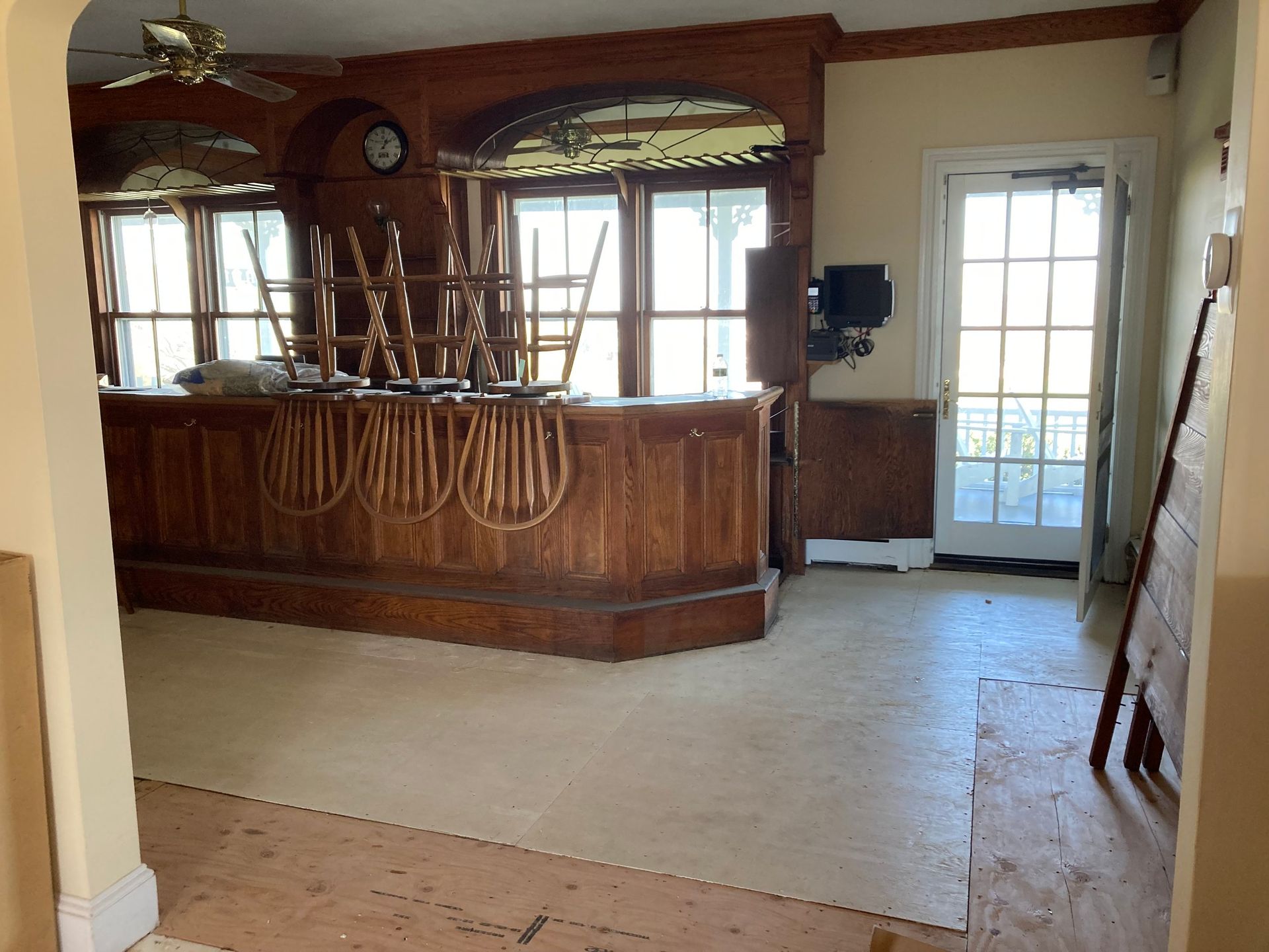 Interior of a wooden bar, with stacked chairs. A glass door is visible.